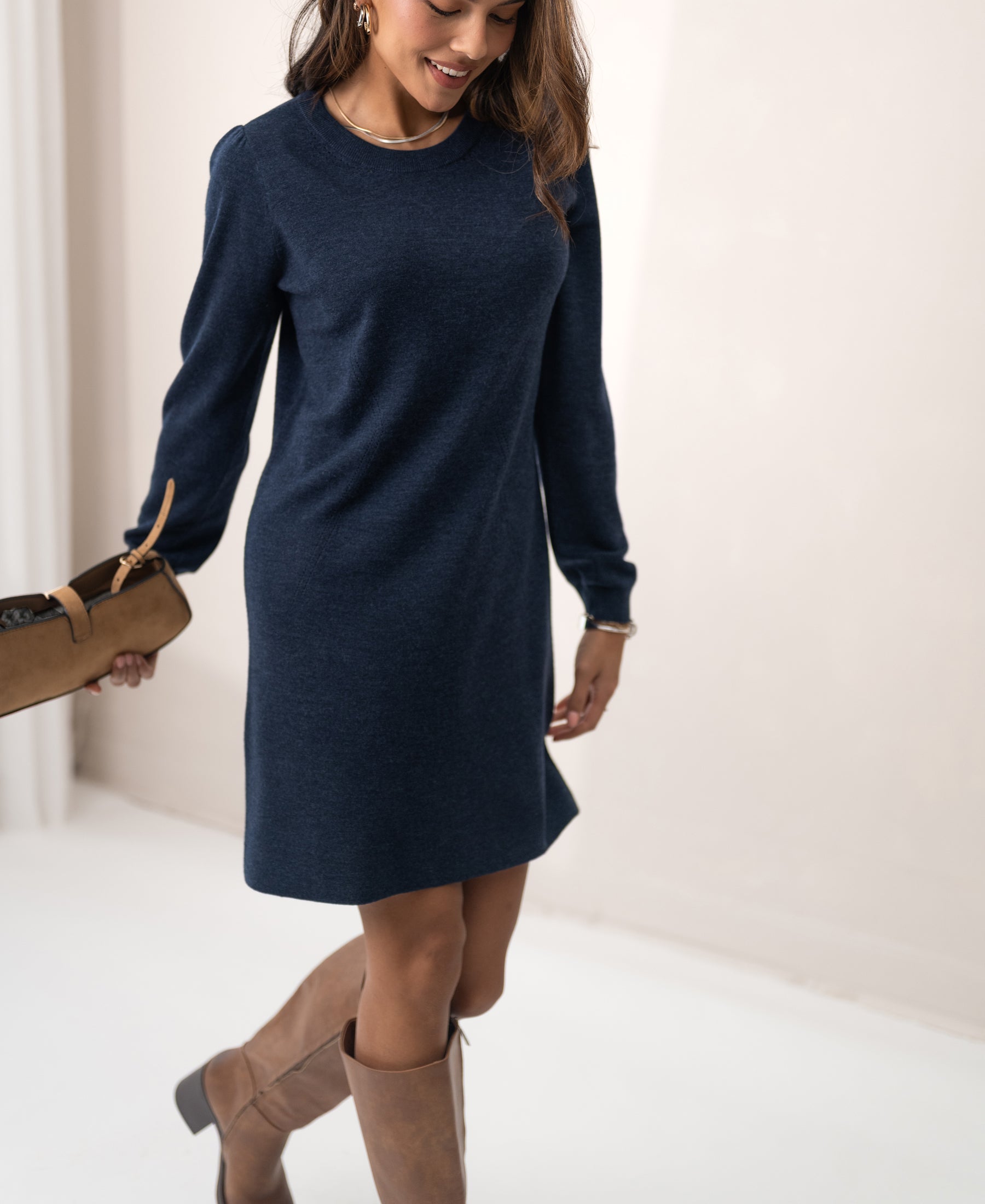 Woman wearing the PLEIN PUBLIQUE LA MIMI merino wool dress in denim blue, standing in a minimal room.
