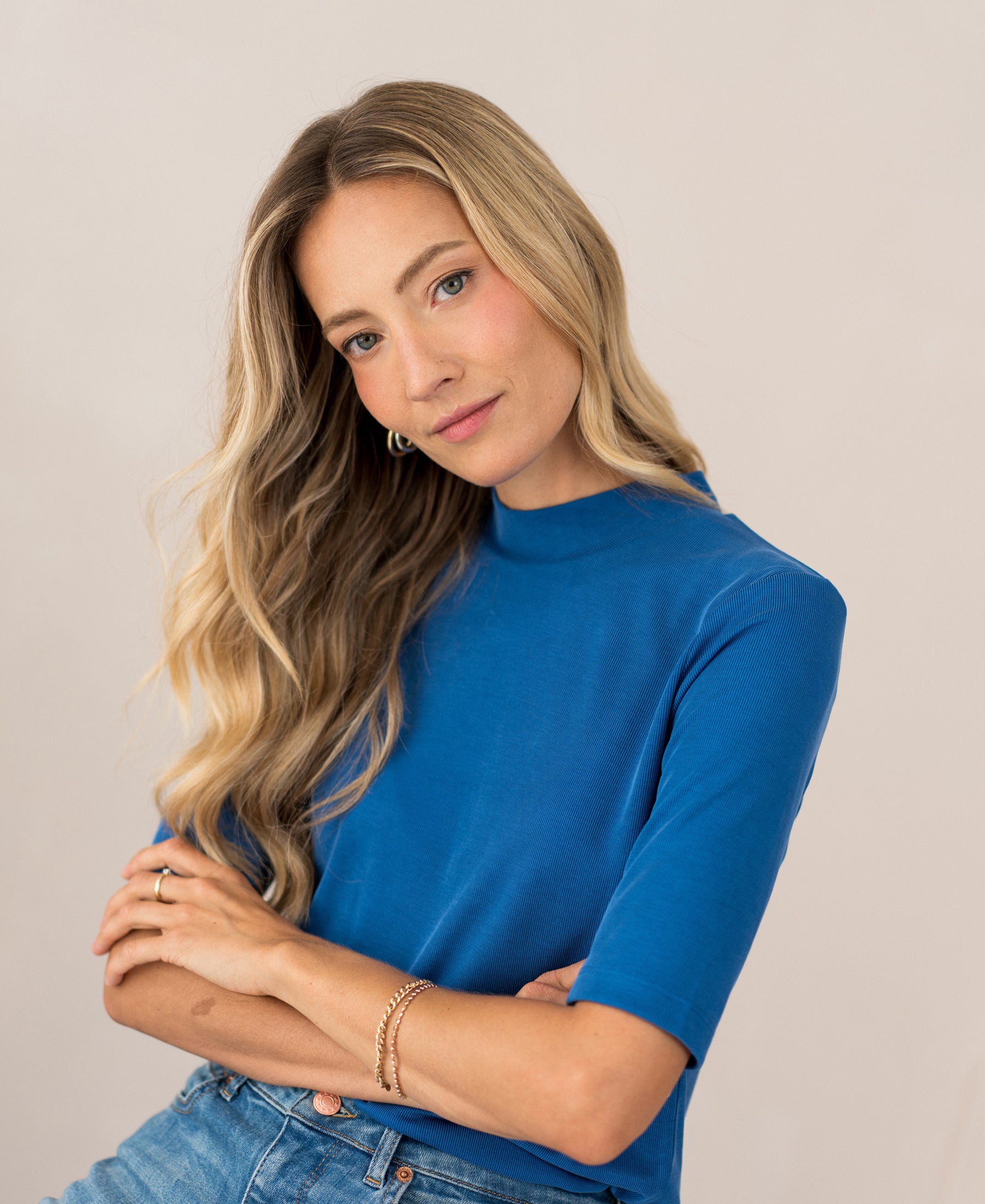 Cobalt blue ribbed collared top worn by a woman, arms crossed.