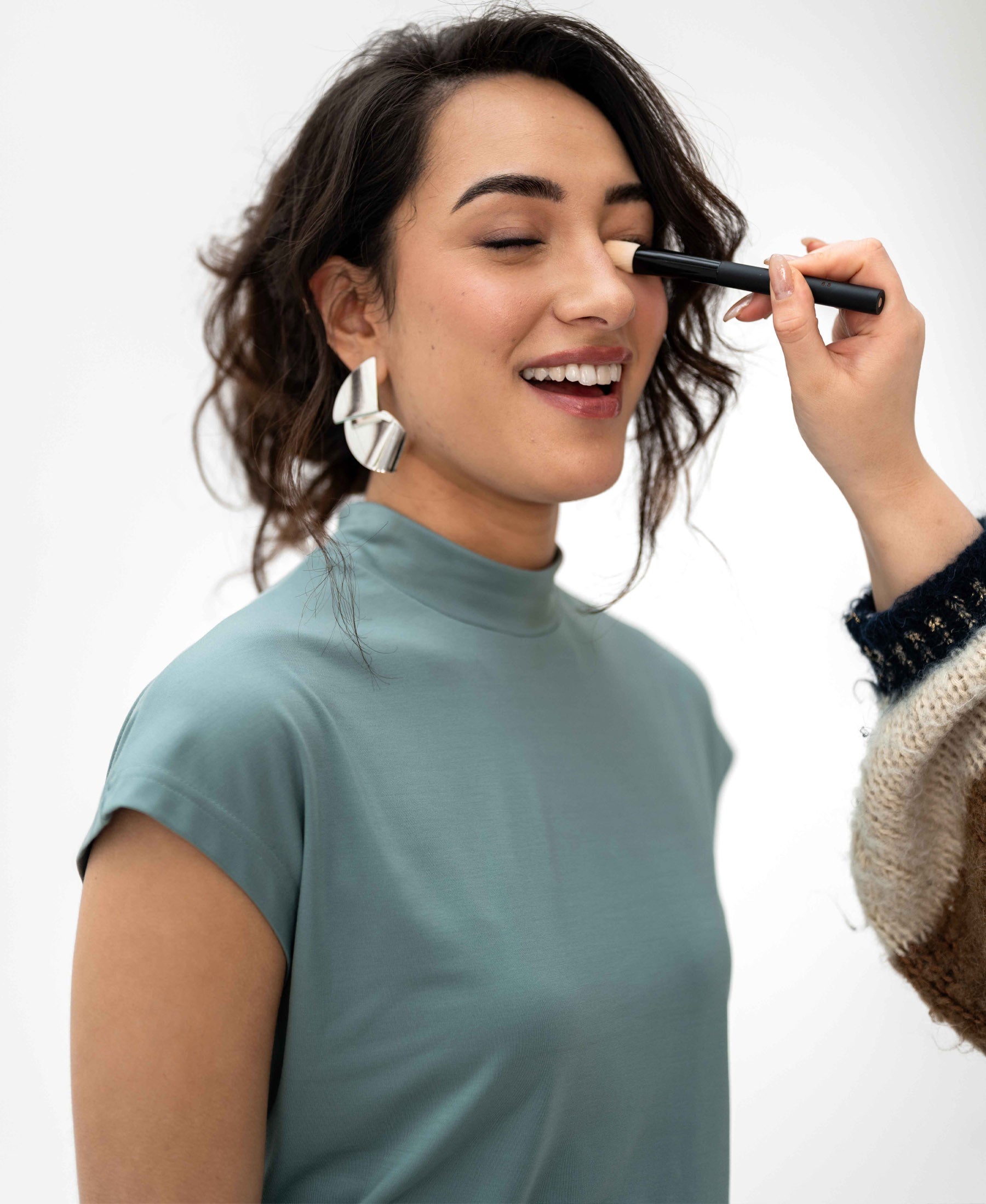 Mist green PLEIN PUBLIQUE LA ROMY travel top shown on woman with eyes closed, smiling.