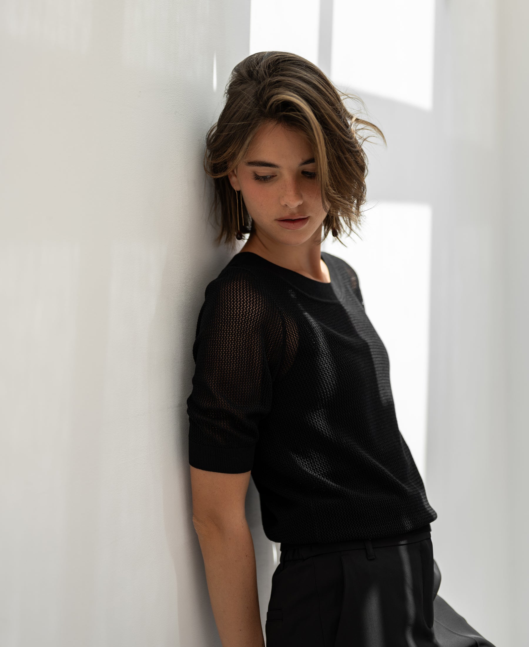 Black mesh sweater with silk by PLEIN PUBLIQUE, shown from the front against a white wall.