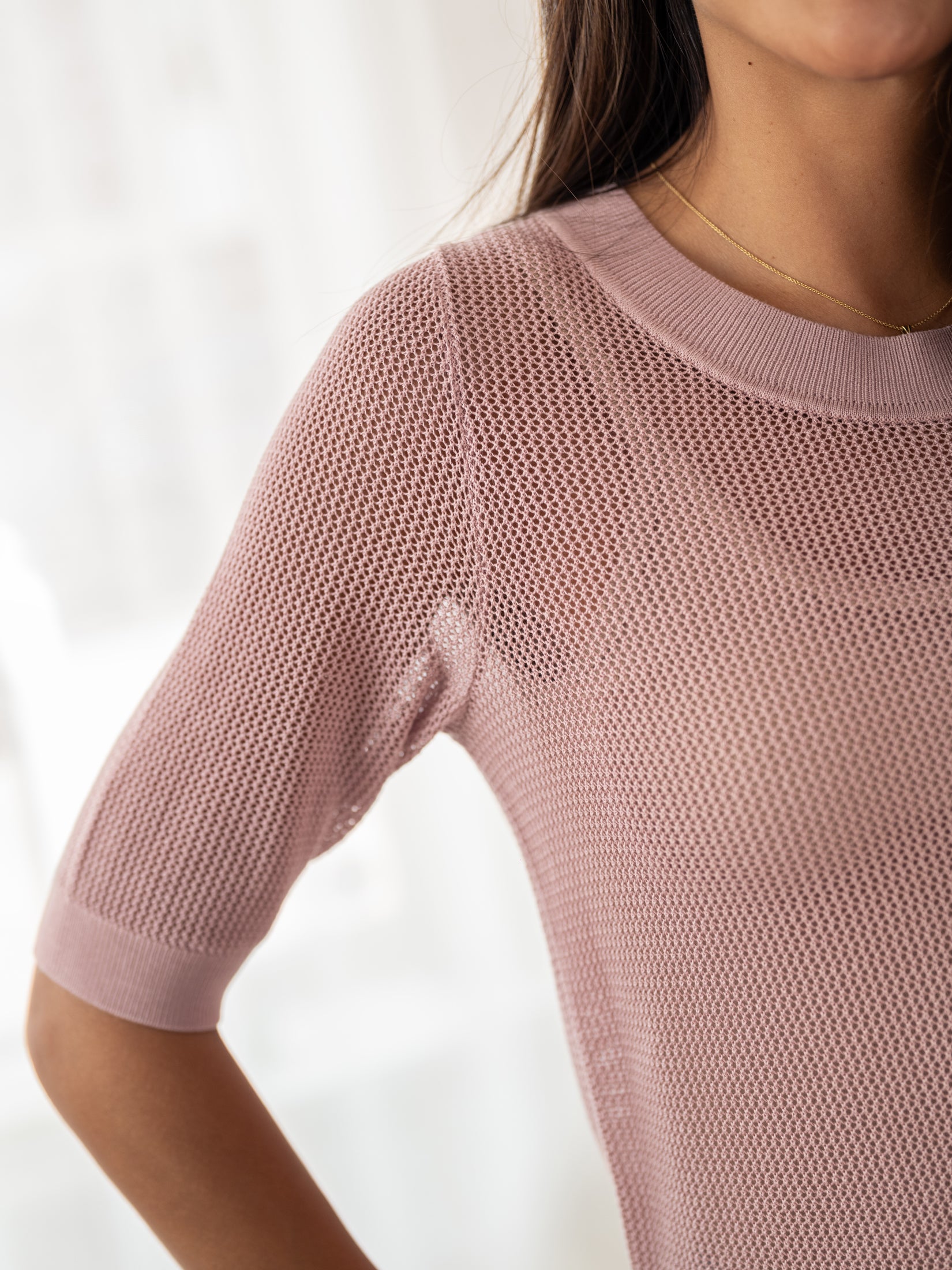 Dusty pink mesh sweater with silk, shown neck to waist, arm bent.