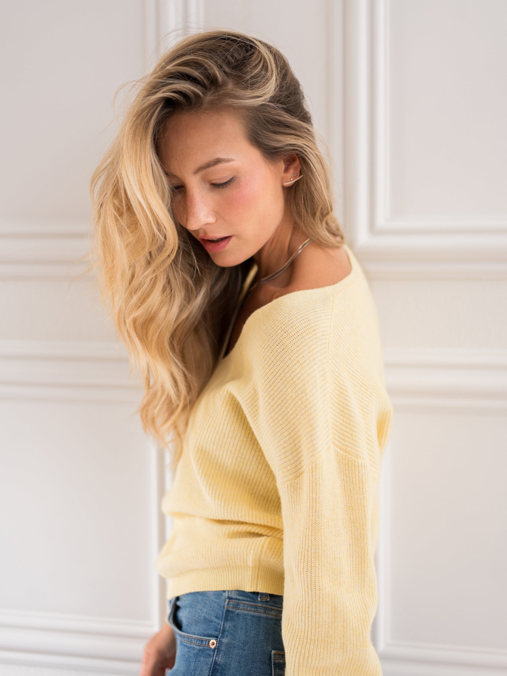 Yellow Merino wool LE PAPILLON Mimosa sweater by PLEIN PUBLIQUE shown against a white paneled wall.
