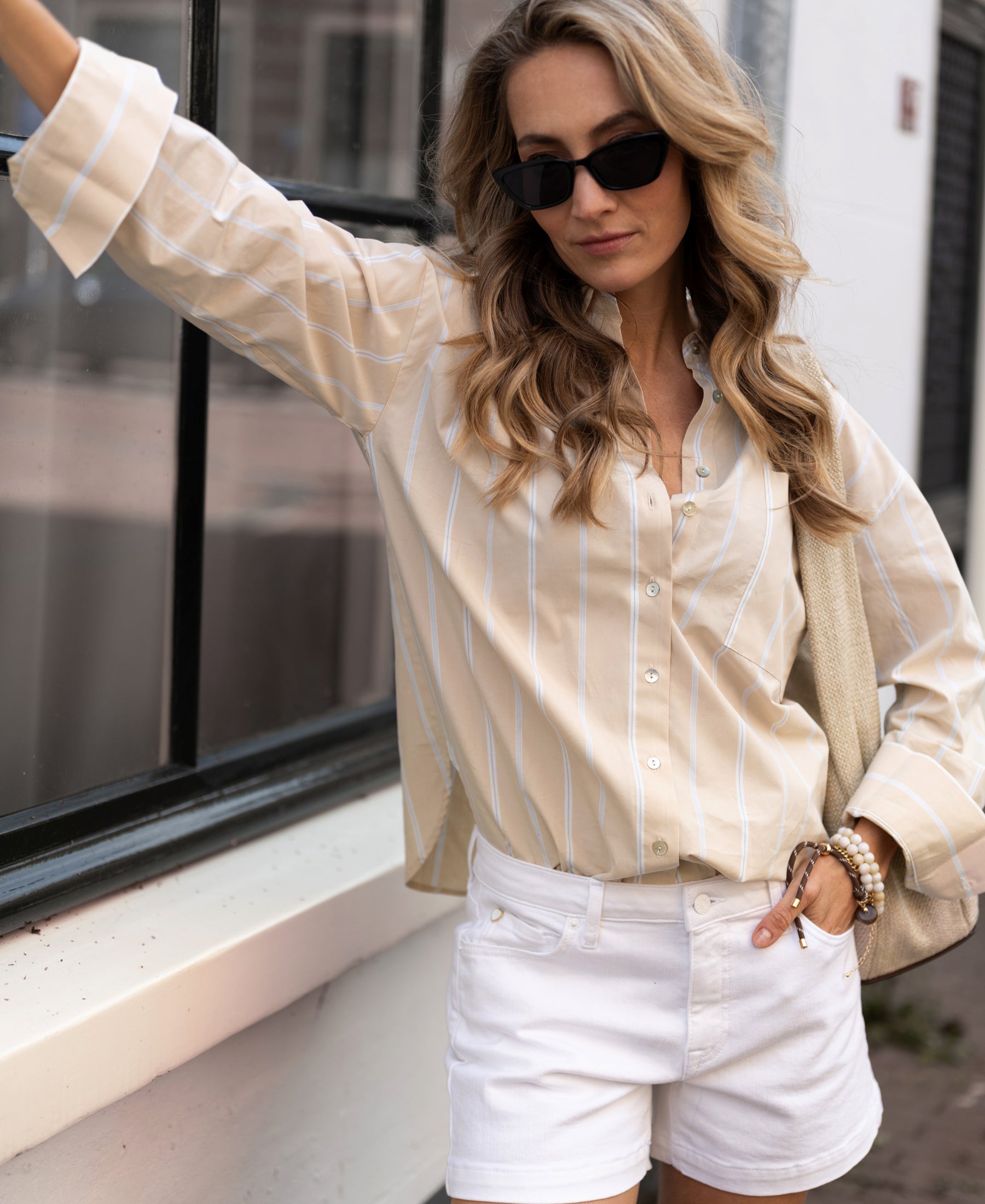 Woman wearing a PLEIN PUBLIQUE LA PASCALLE sand-light blue striped blouse outdoors.