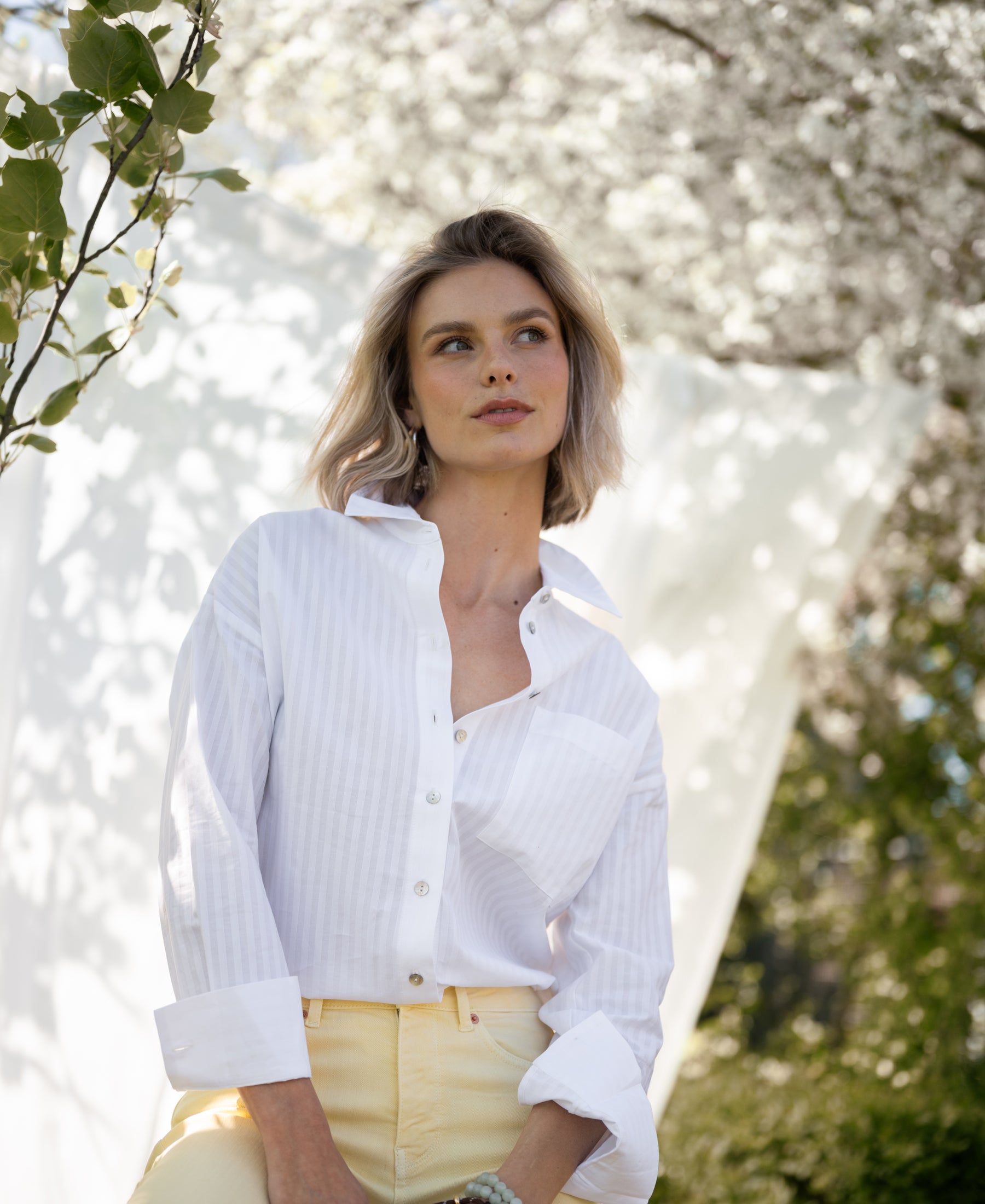 White striped PLEIN PUBLIQUE LA PASCALLE blouse shown outdoors in soft sunlight.