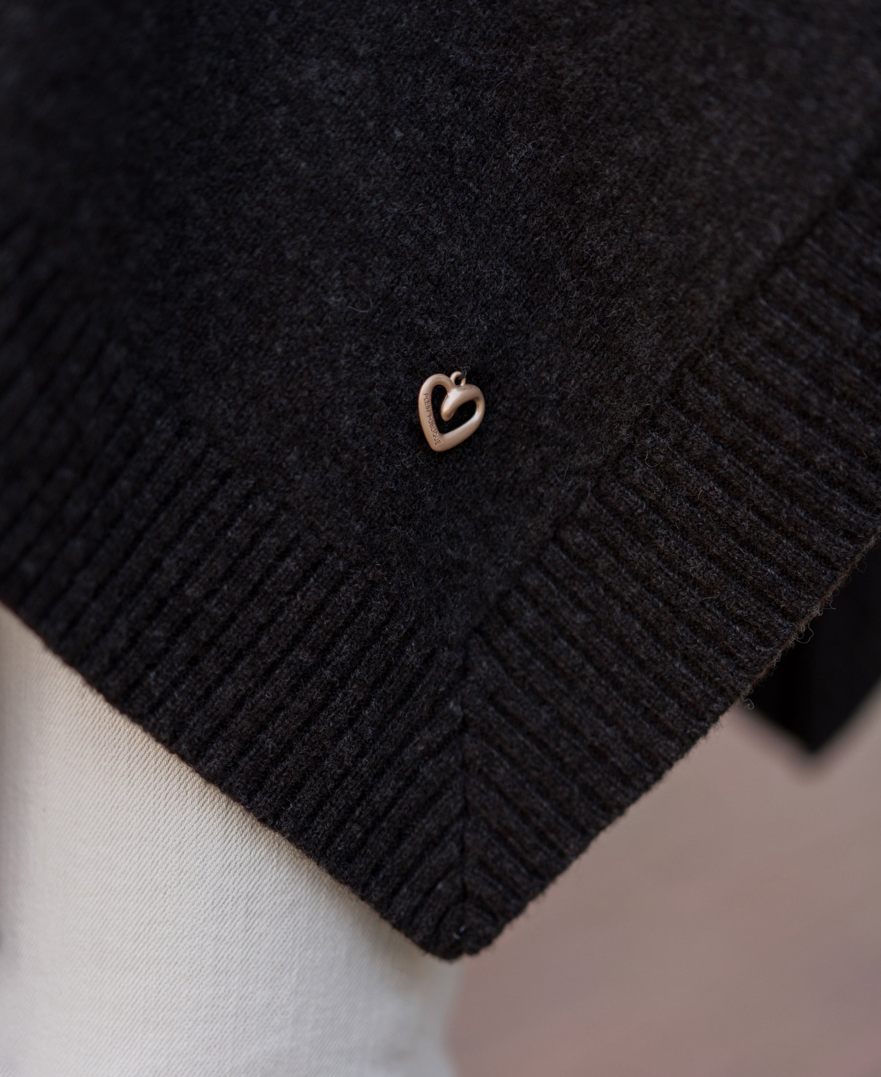 A small heart charm adorns the Pure Chocolate Merino Wool Poncho, draped elegantly.