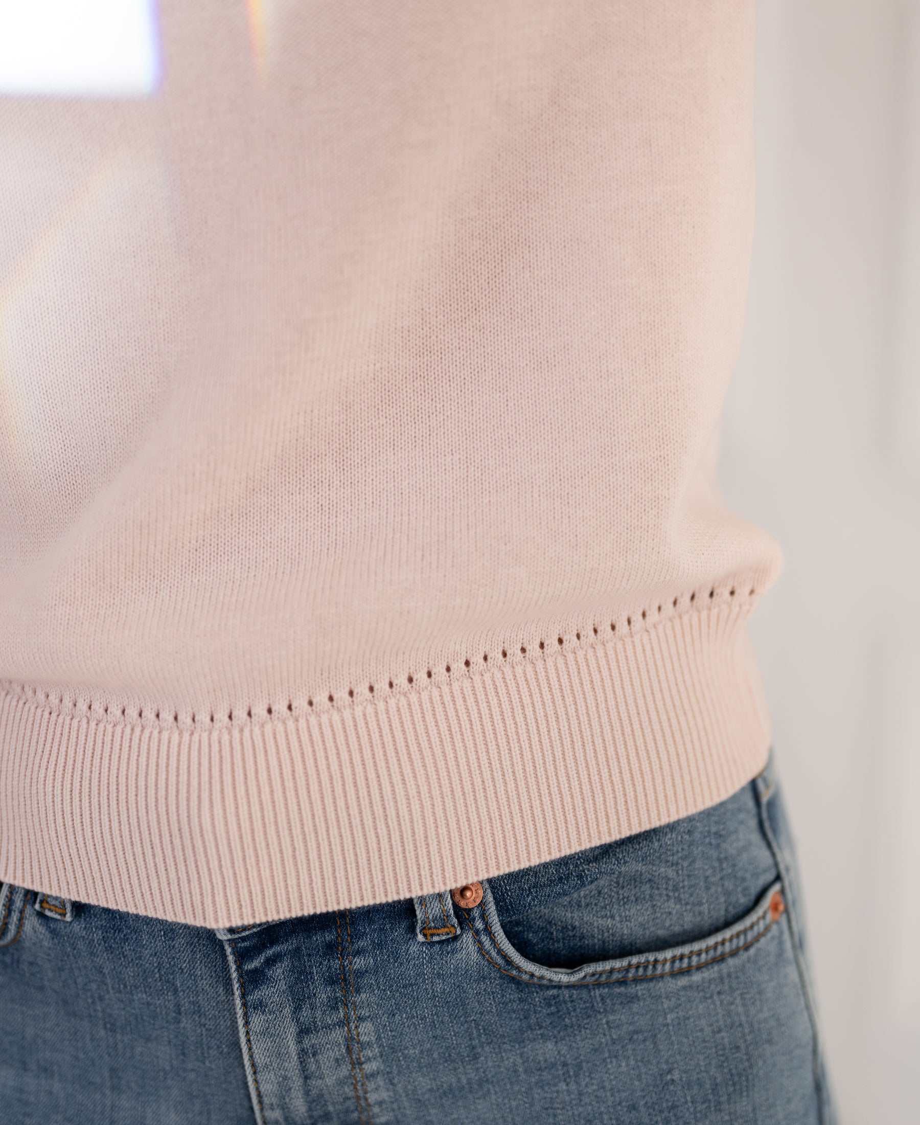 Close-up of a blush pink sweater, highlighting the hem and side seam.