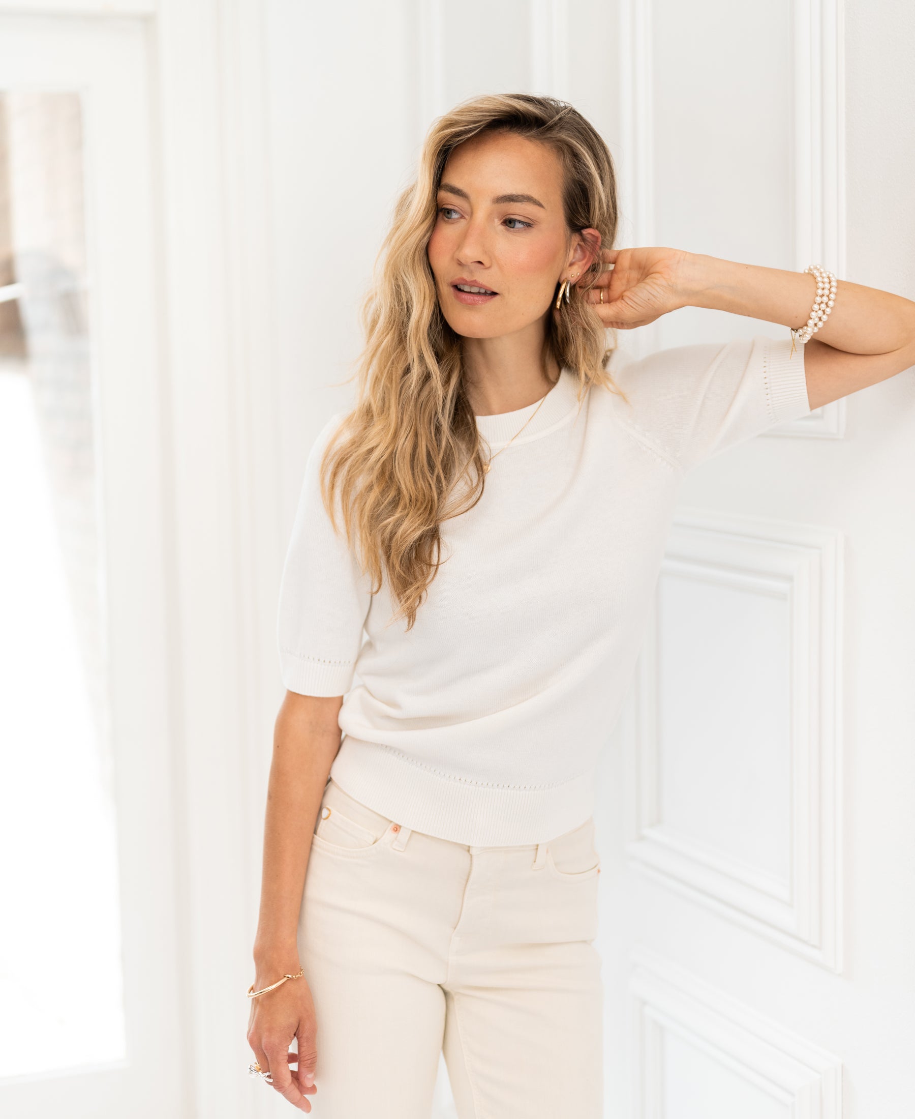 White knit LA REVE sweater by PLEIN PUBLIQUE displayed against a white paneled wall.