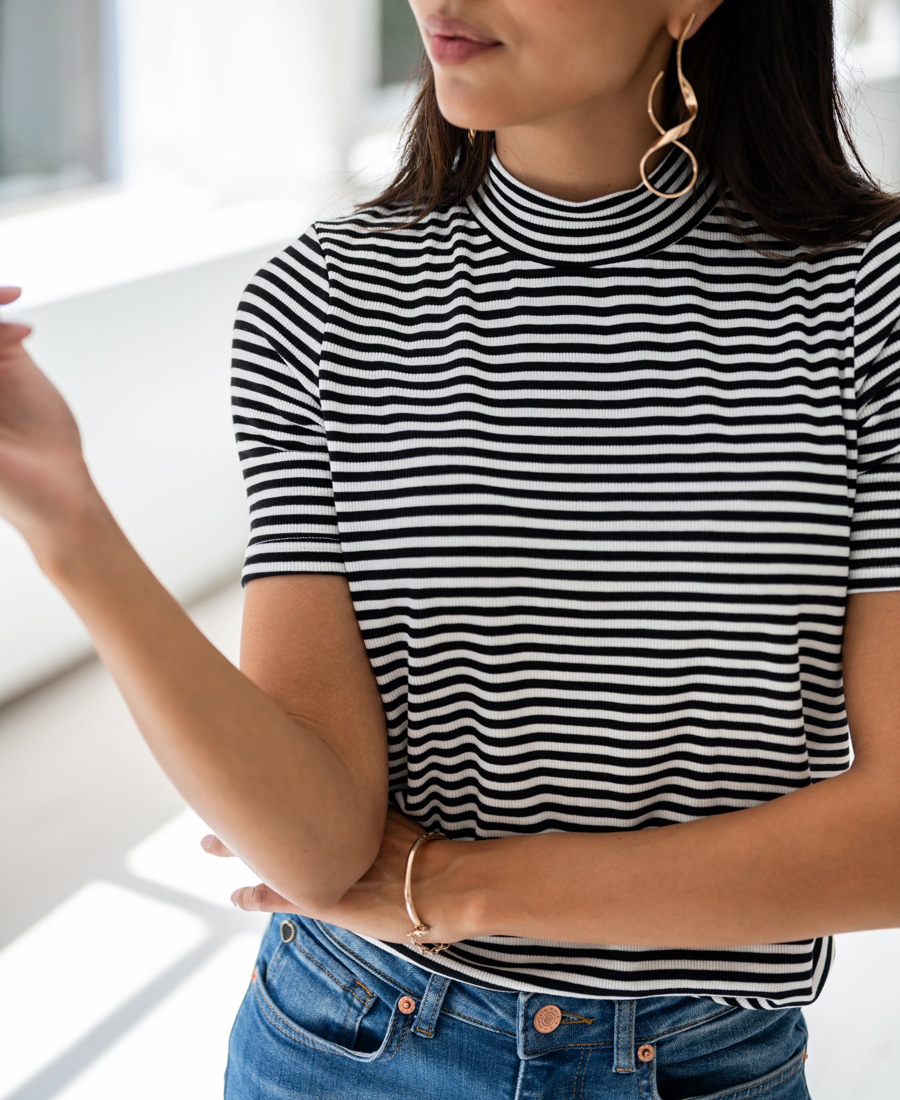 Ribbed high-neck top in white-black by PLEIN PUBLIQUE, shown on a woman with arms slightly crossed.