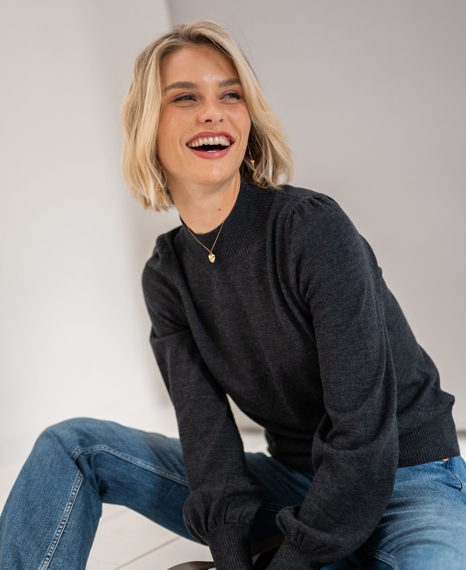 Woman wears the LES SALLES Anthracite Turtleneck Sweater by PLEIN PUBLIQUE against a light background.