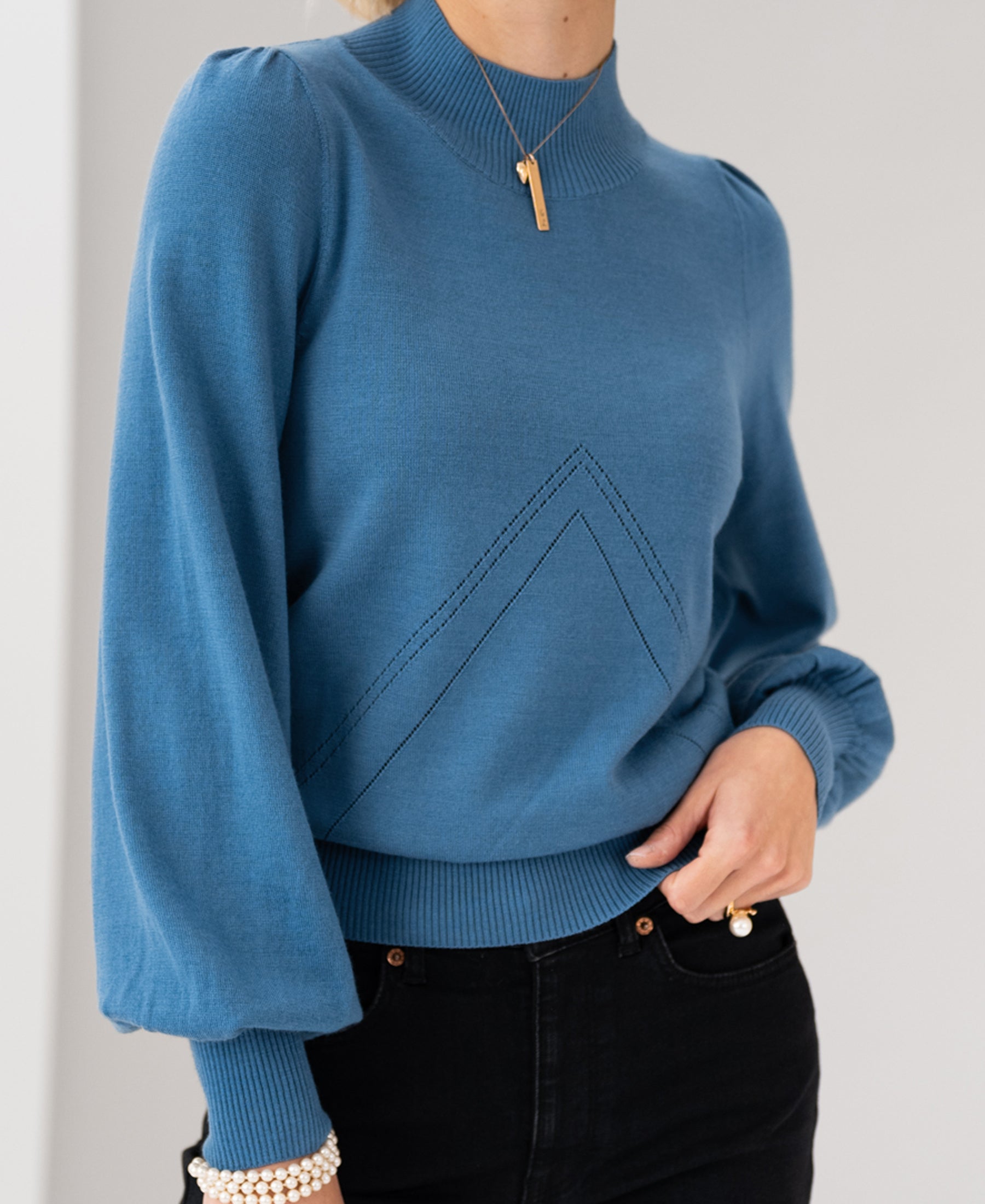 Woman wearing a blue Plein Publique turtleneck sweater.