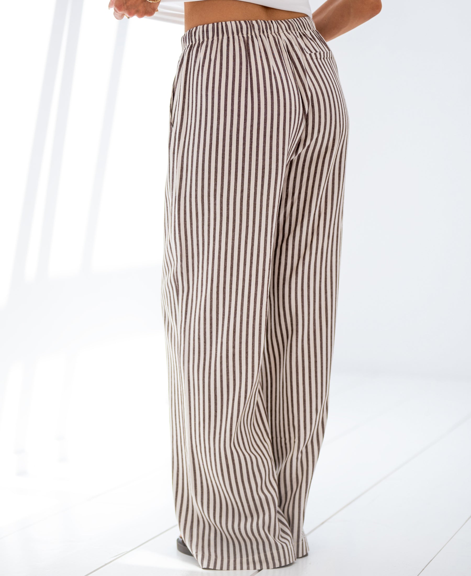 Brown striped linen-blend trousers on a white floor.