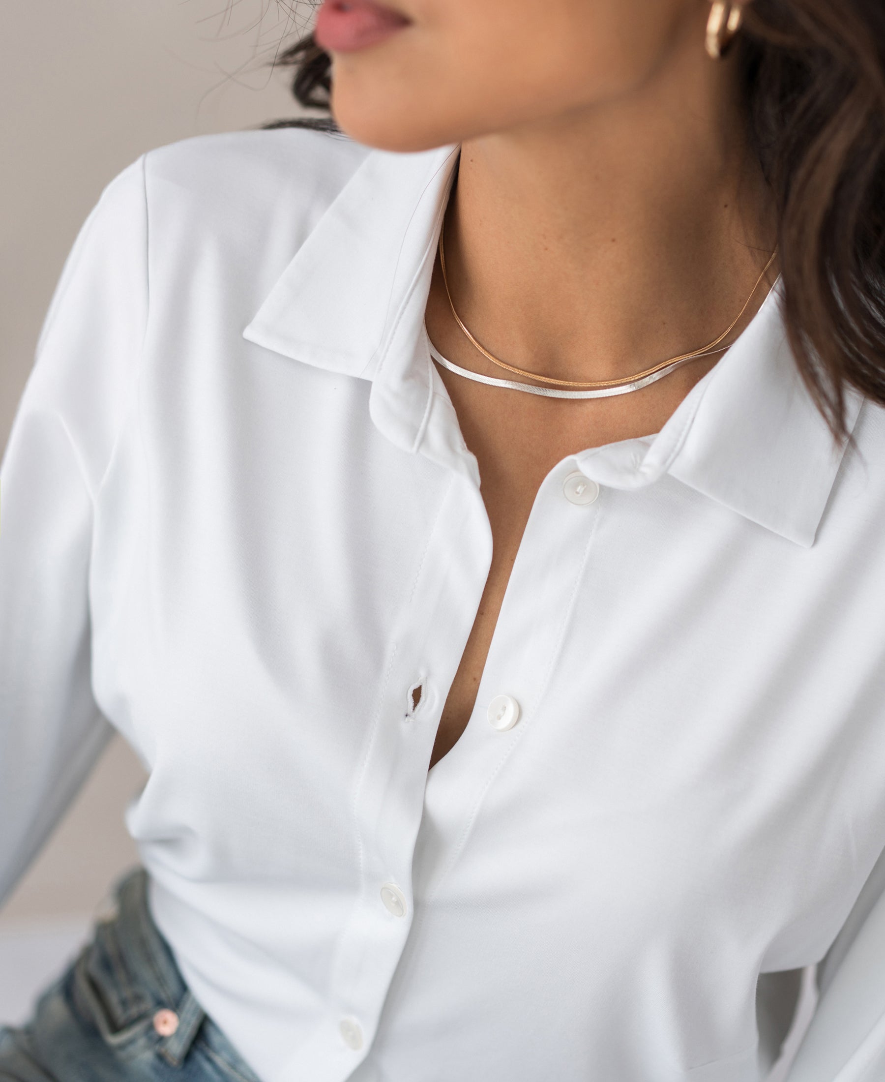Woman wearing a white travel blouse, seated.