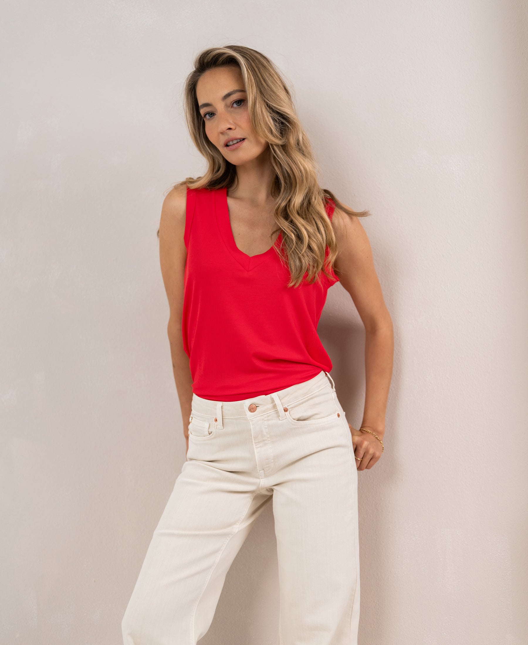 Woman wearing a coral Lyocell LA SIRA top by PLEIN PUBLIQUE, standing and looking at the camera.