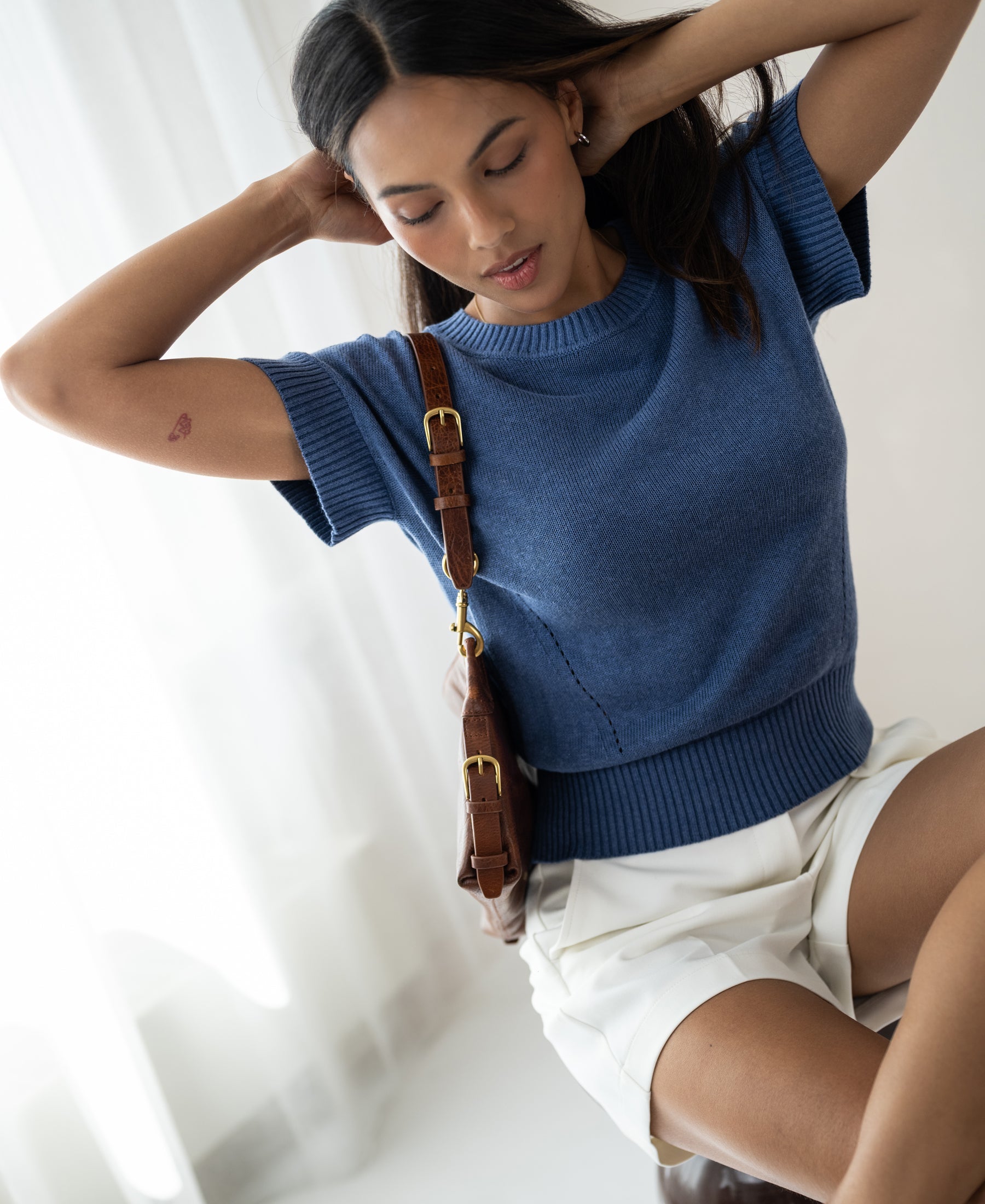 Woman wears a PLEIN PUBLIQUE summer sweater with linen in denim blue.
