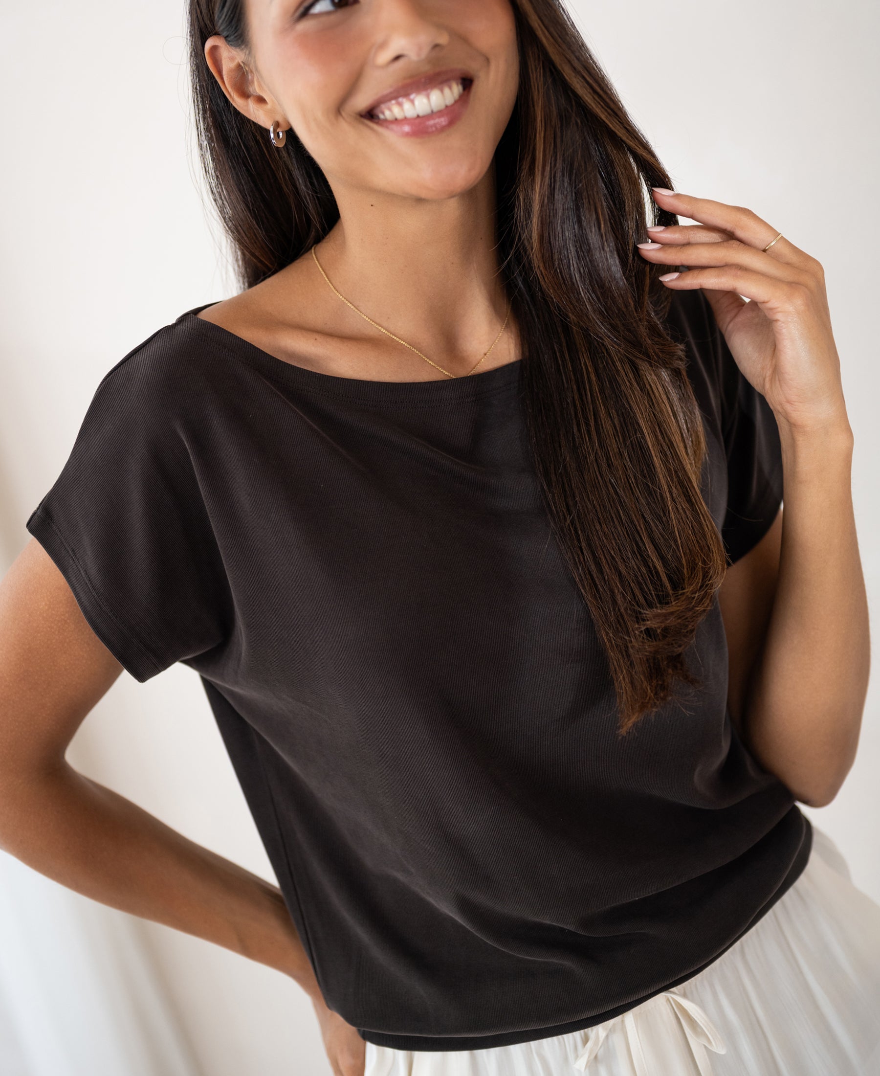 Woman wearing a ribbed boat neck T-shirt in dark brown from PLEIN PUBLIQUE.