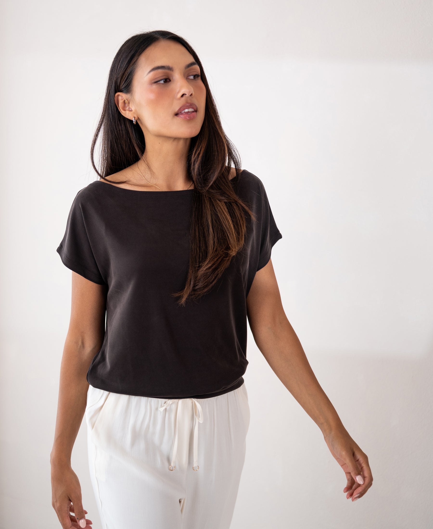 Woman with long dark hair wears a rib boat neck T-shirt in pure chocolate brown by PLEIN PUBLIQUE.
