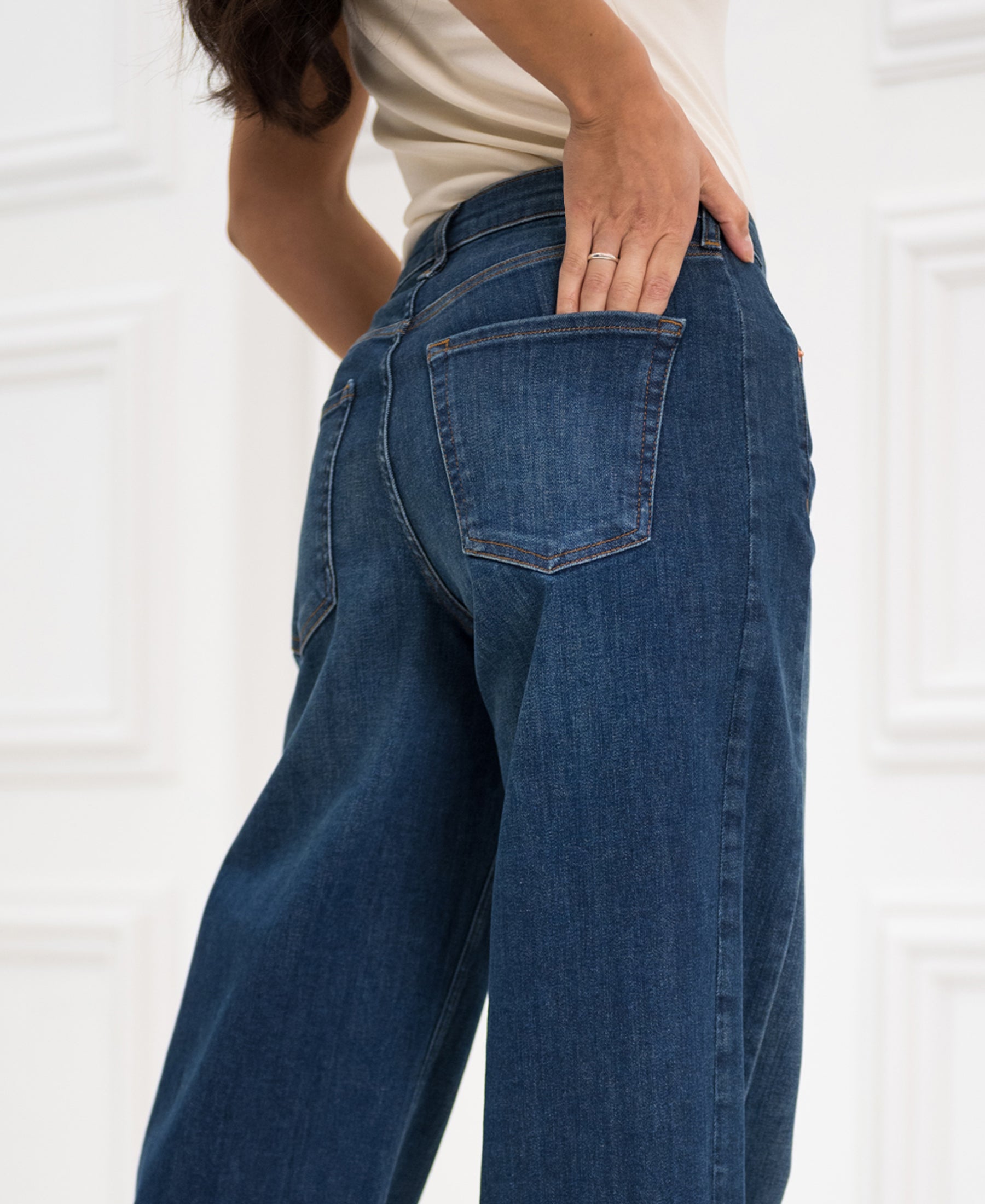 Wide leg blue heritage jeans, hand on back pocket, seen from behind.