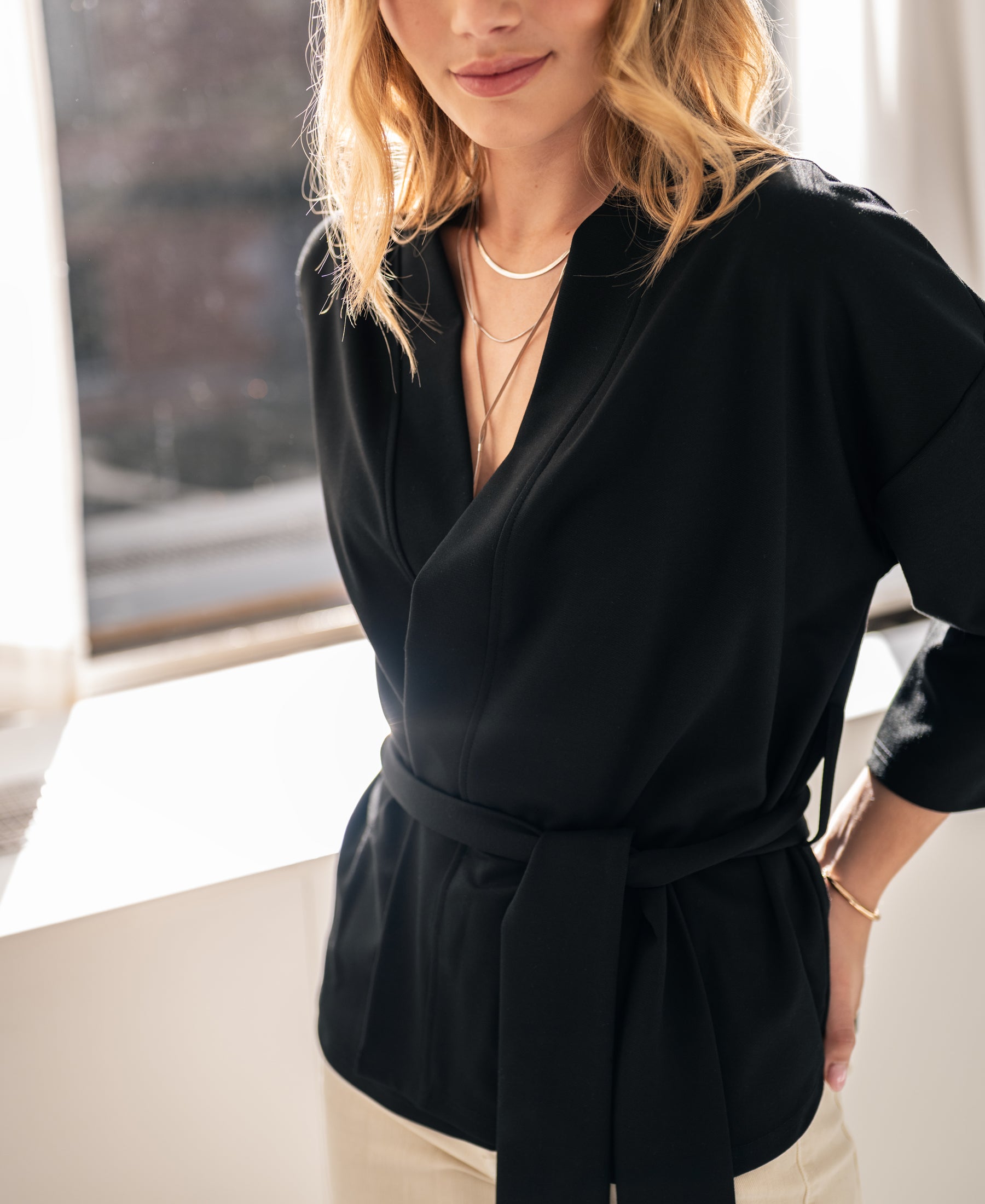 Black kimono wrap cardigan by OVERIG, shown near a sunlit window.
