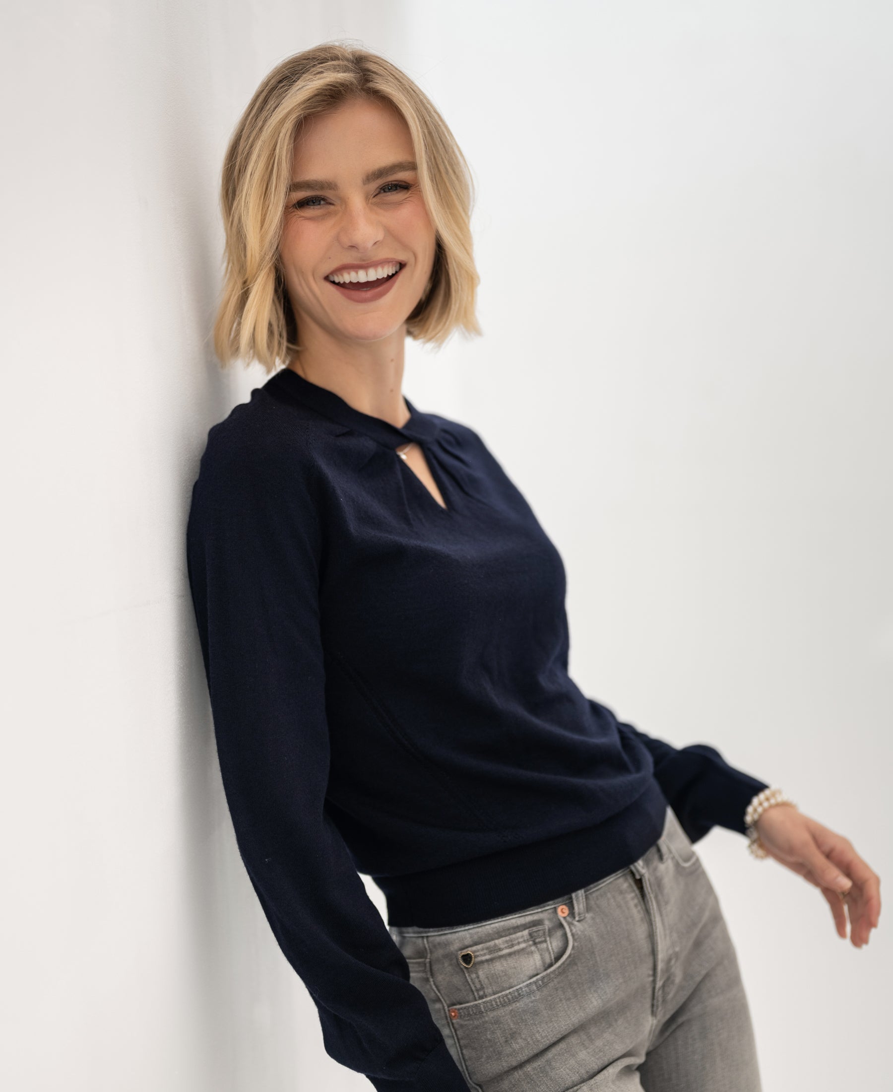 Woman wearing a PLEIN PUBLIQUE dark blue merino wool sweater, seen from the front.