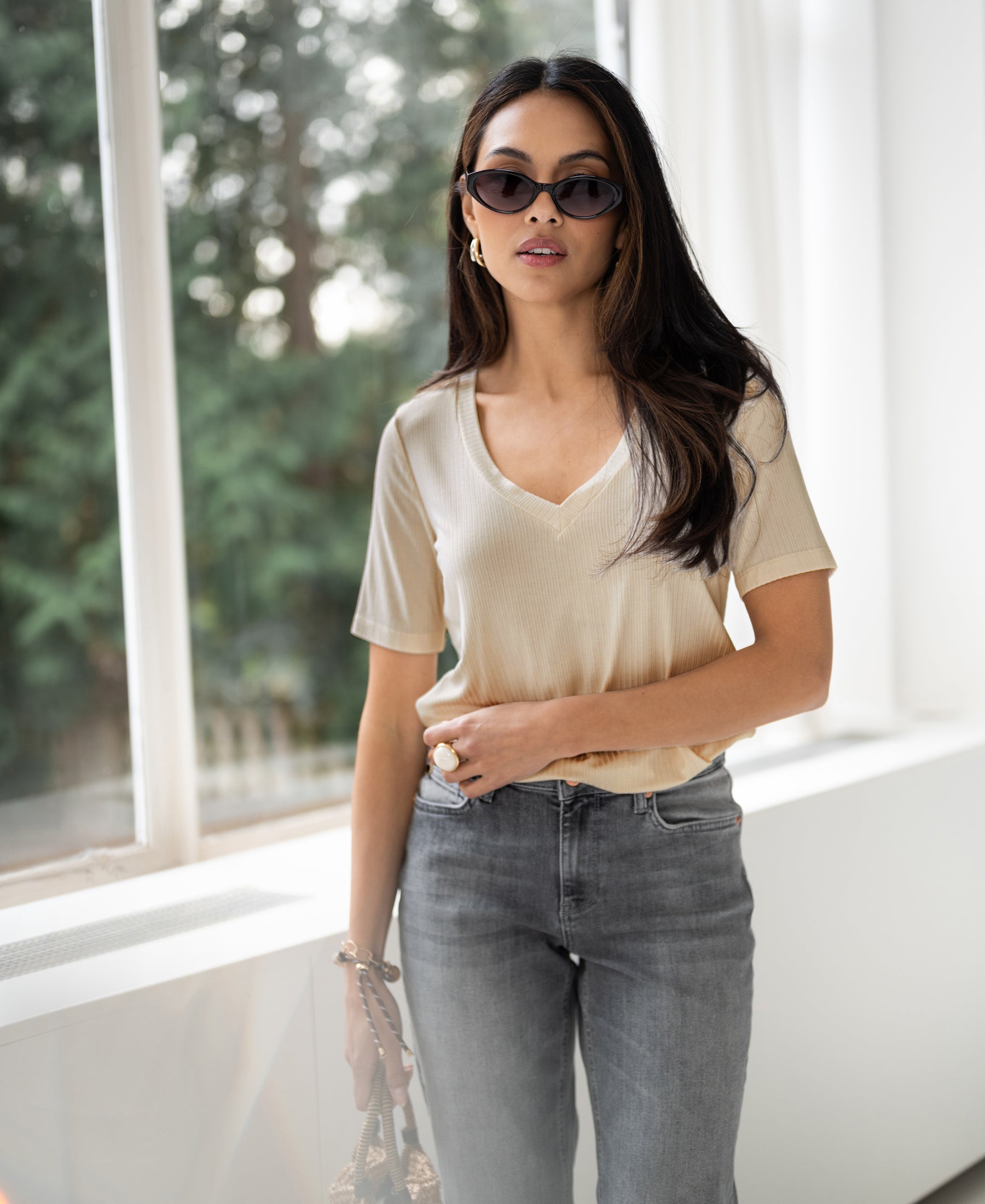 Light sand bamboo T-shirt, front view, worn by model standing indoors near window.
