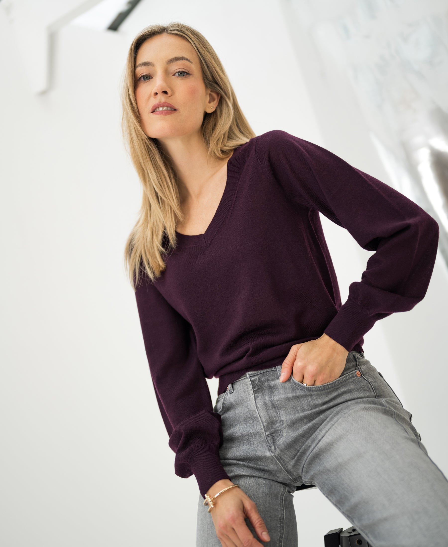 Merino wool V-neck sweater in aubergine by PLEIN PUBLIQUE shown in a bright room.