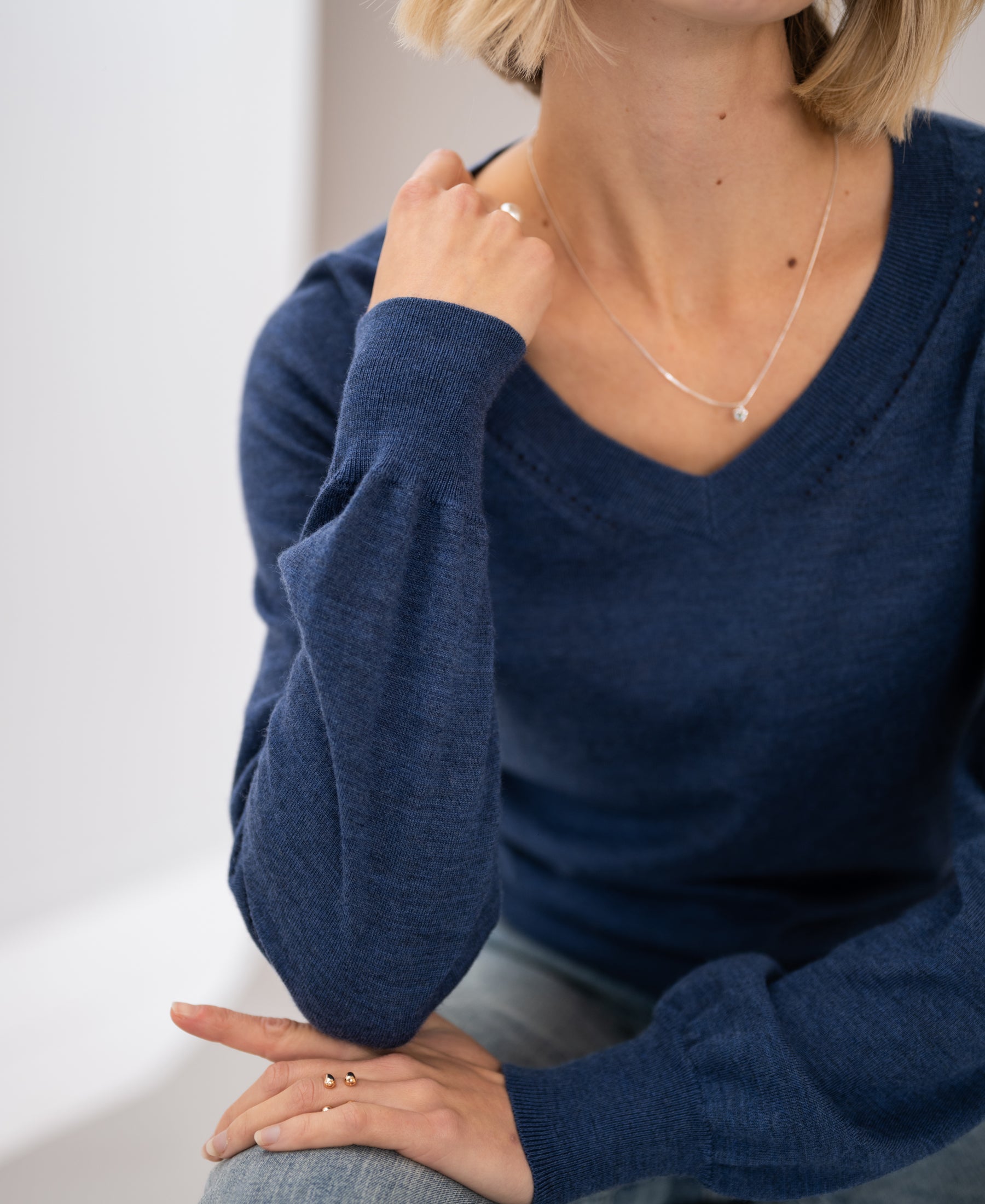 Woman wearing an indigo blue PLEIN PUBLIQUE Merino wool V-neck sweater.