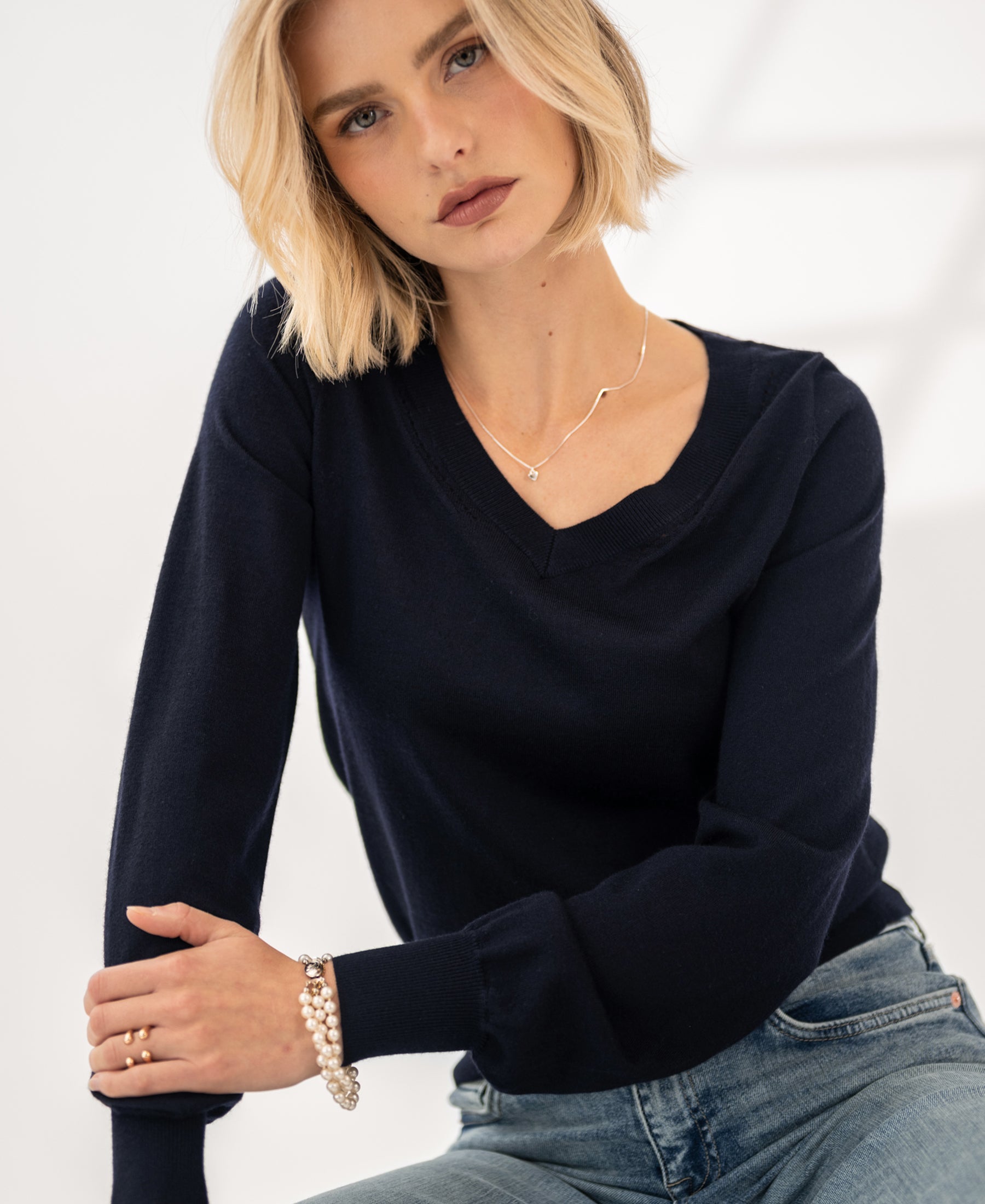 Woman wearing PLEIN PUBLIQUE Merino V-neck sweater LA VILLE dark blue indoors.