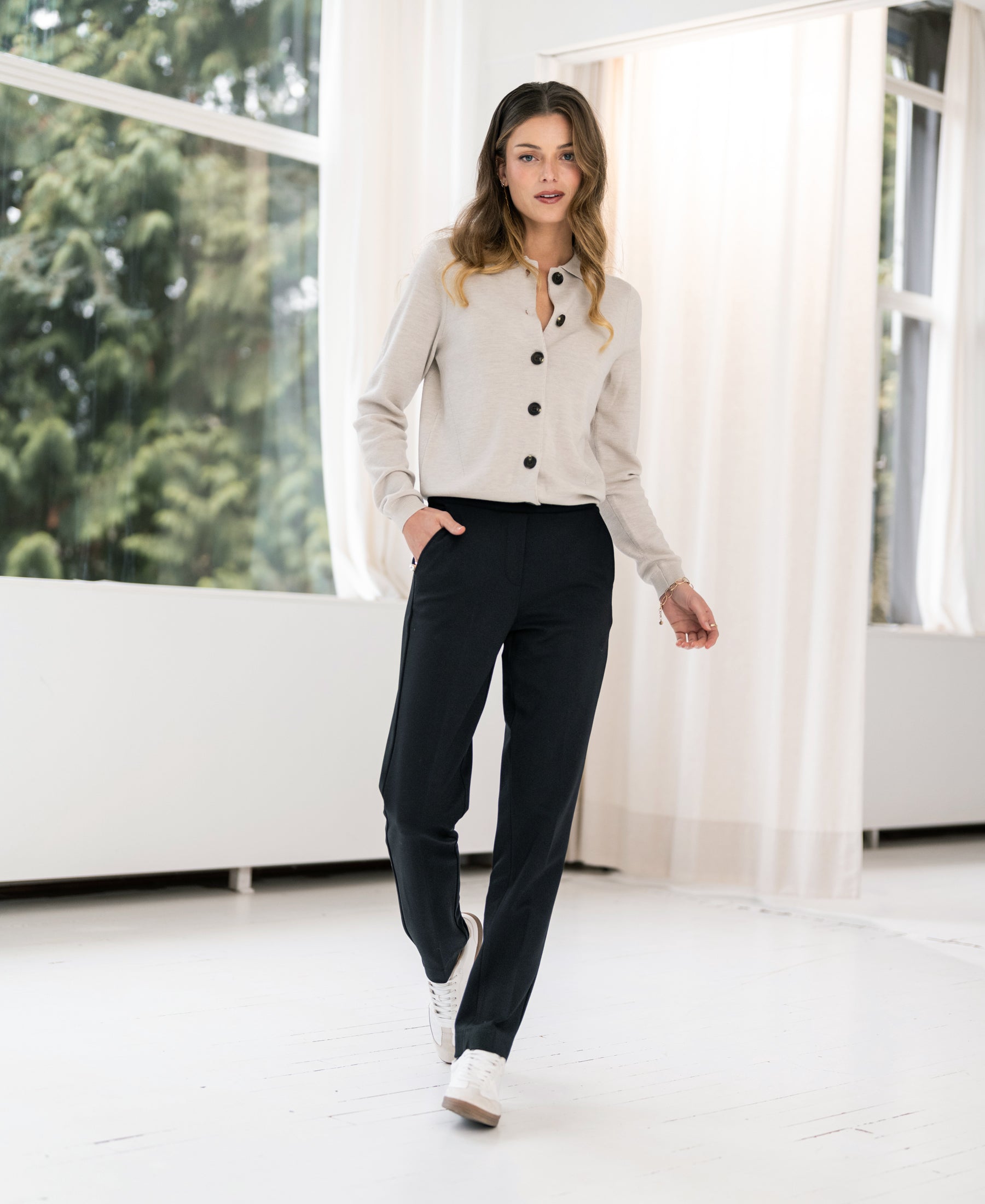 Woman wearing black PLEIN PUBLIQUE LA ROBYN trousers indoors.
