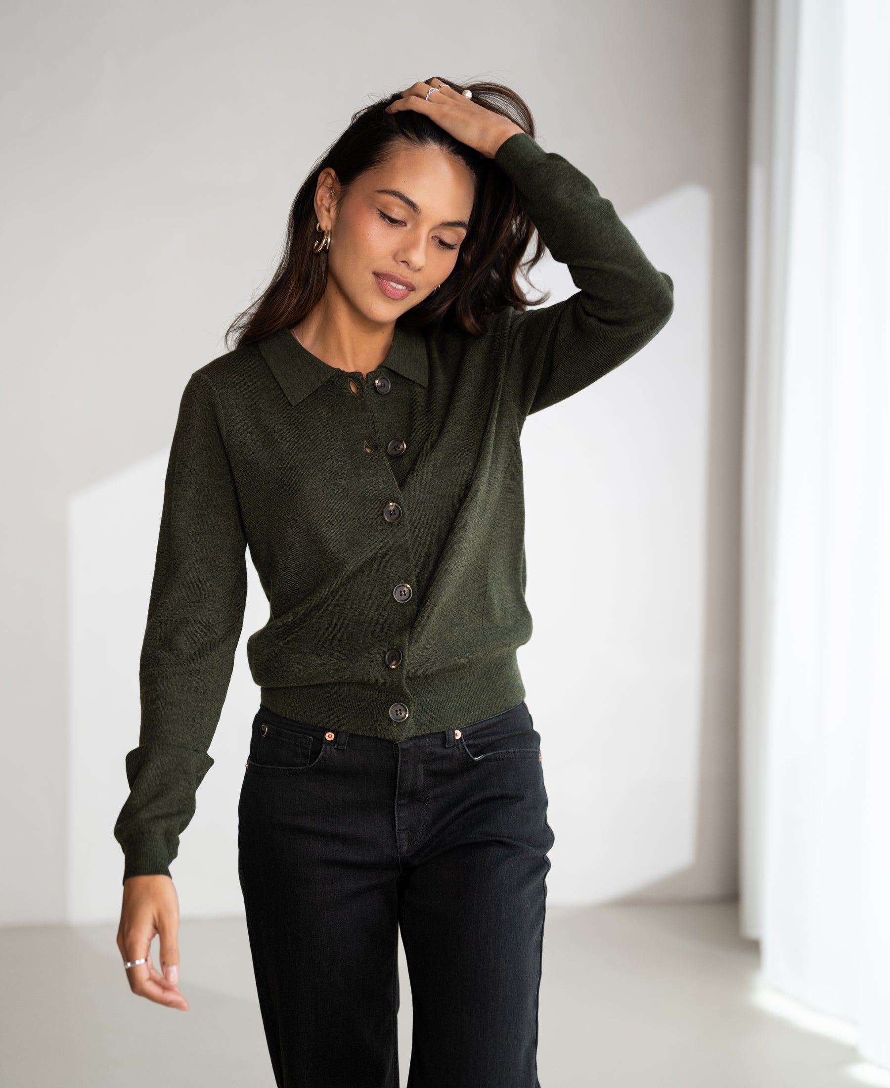 Woman wearing a PLEIN PUBLIQUE LES VINGT polo collar vest in bottle green, shown in soft light.