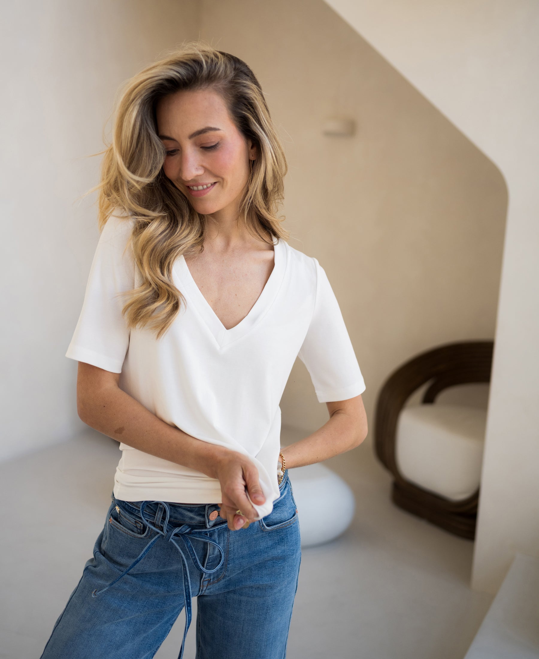 Woman wearing ivory PLEIN PUBLIQUE stretch short sleeve T-shirt LA VOIX, smiling indoors with eyes closed.
