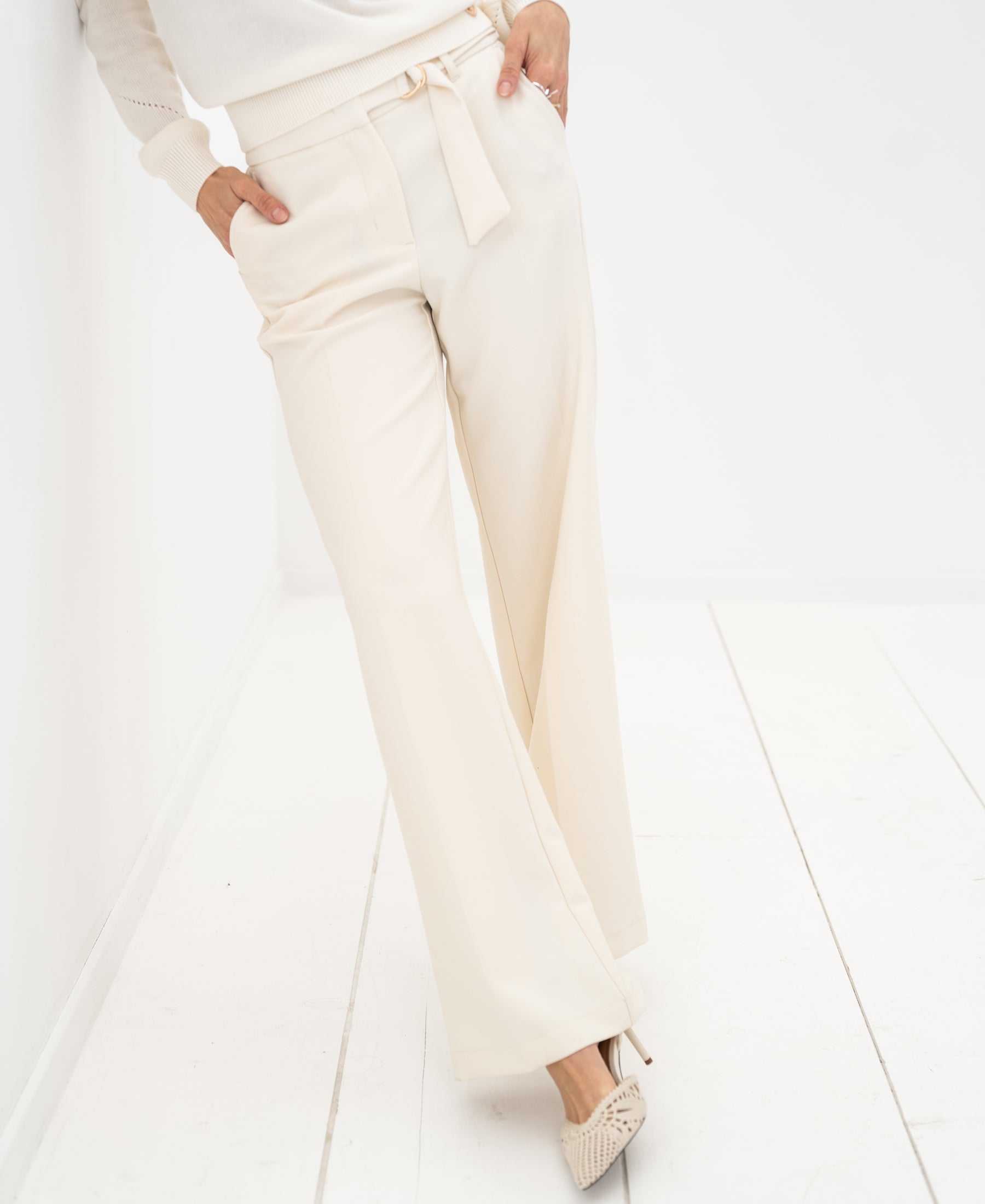 PLEIN PUBLIQUE LA WENDE cream trousers, voor een witte muur.