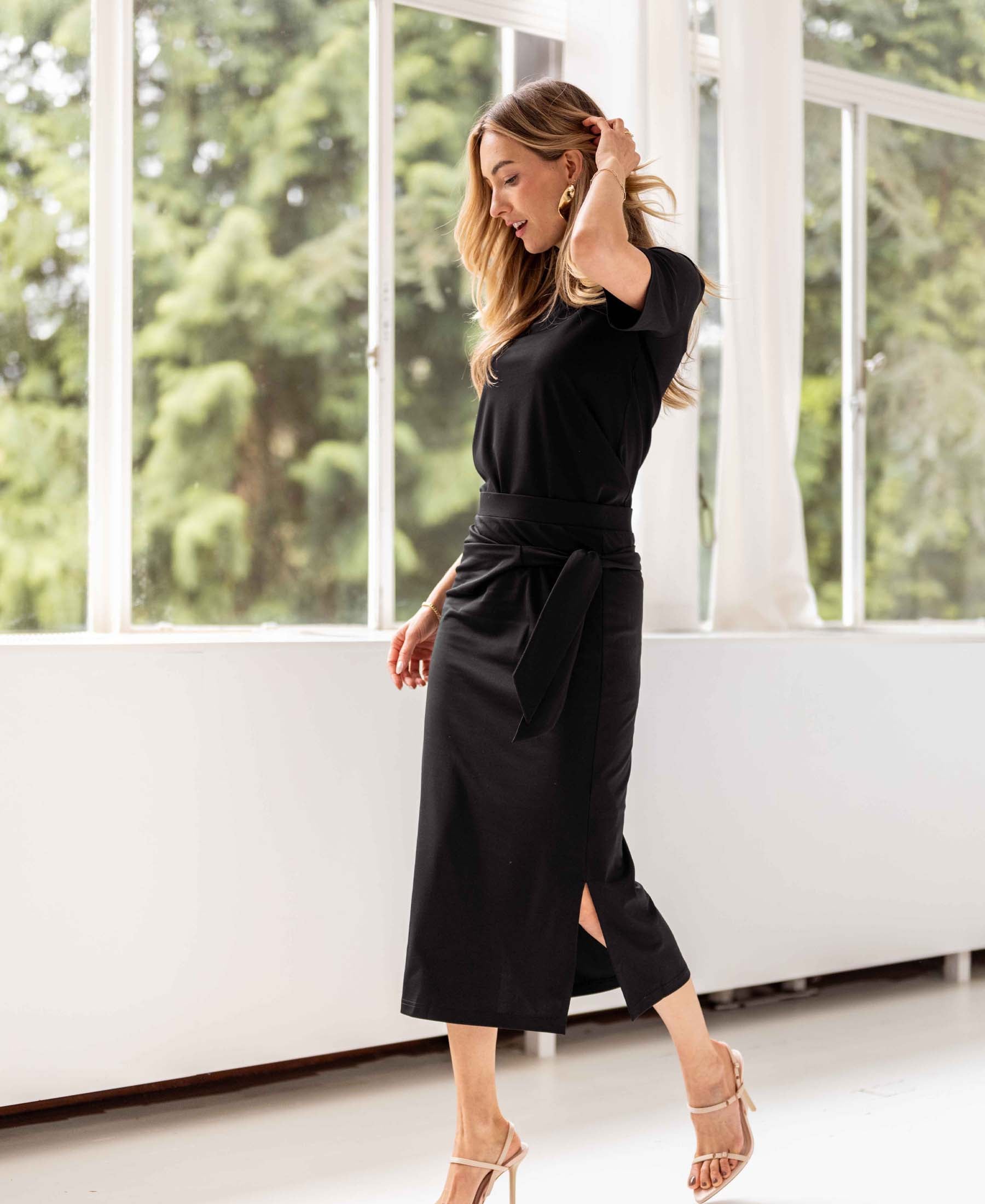 Black travel skirt by PLEIN PUBLIQUE shown indoors near large windows.