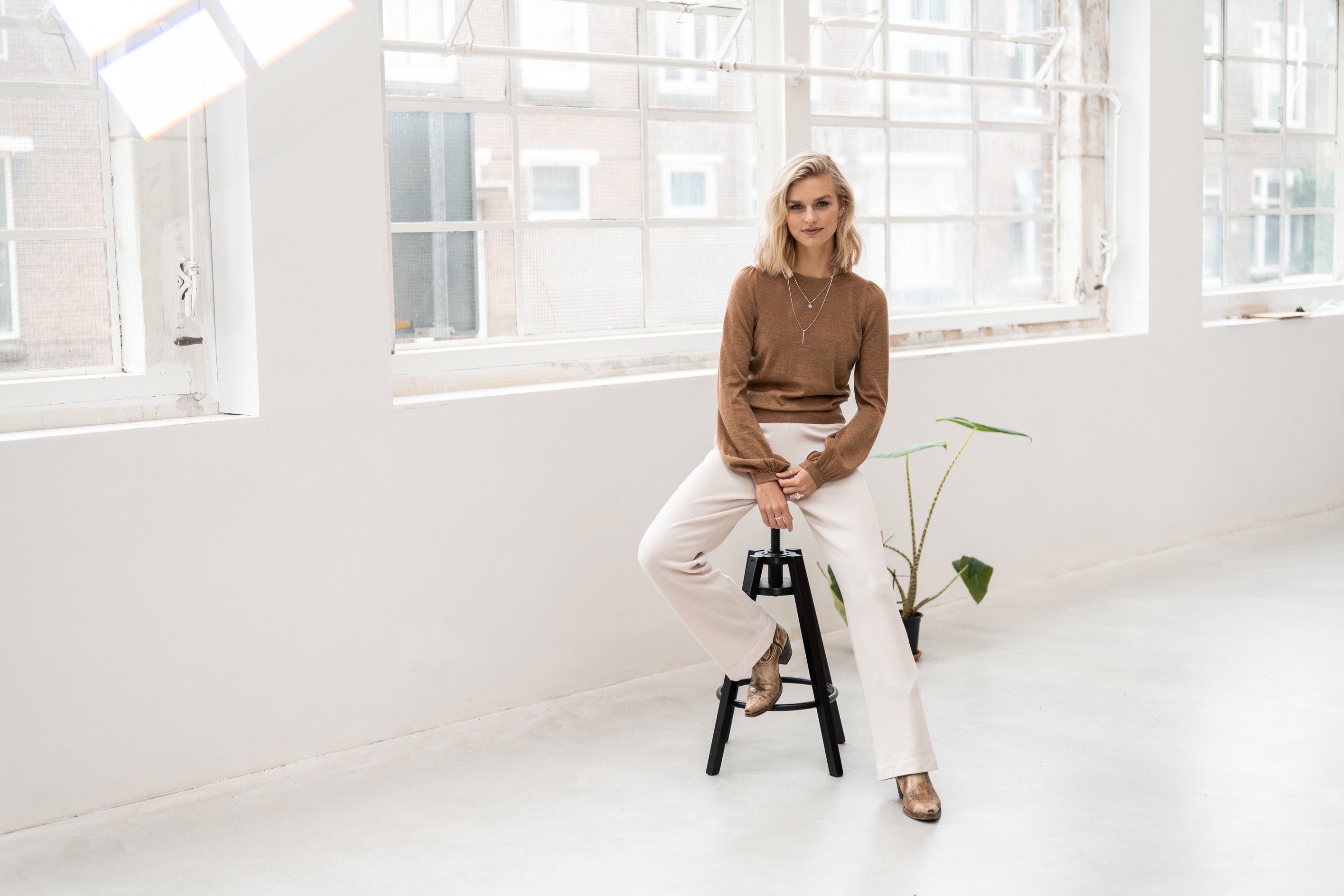 PLEIN PUBLIQUE's Merino wool LA COEUR Chai Tea sweater shown on a model in a bright, airy room.