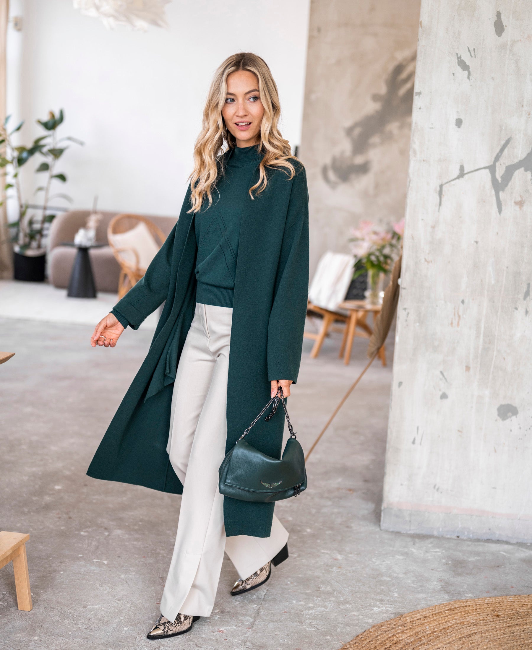 Woman wearing a dark green turtleneck sweater by PLEIN PUBLIQUE.