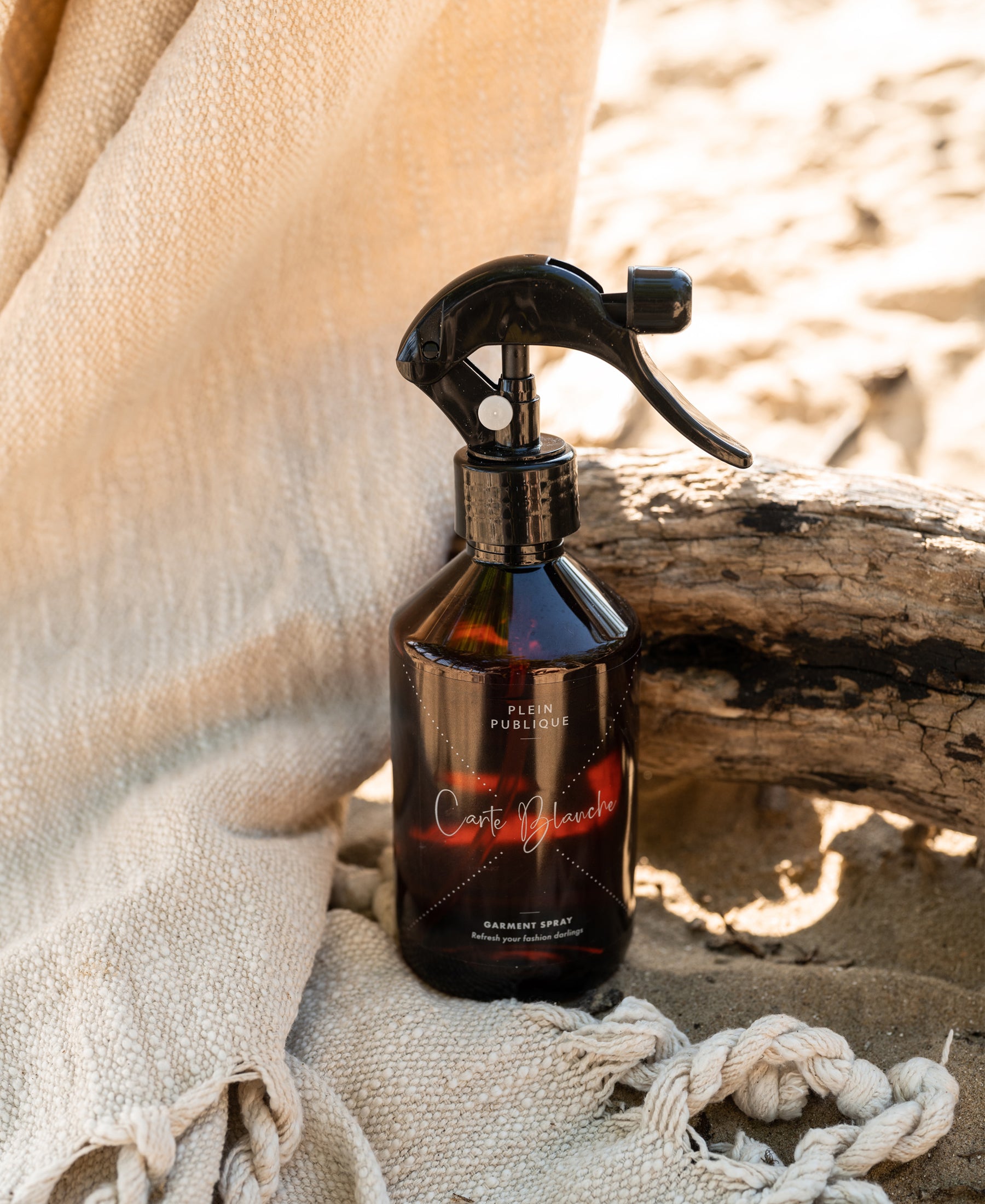 A PLEIN PUBLIQUE clothing fragrance spray bottle on beige cloth.