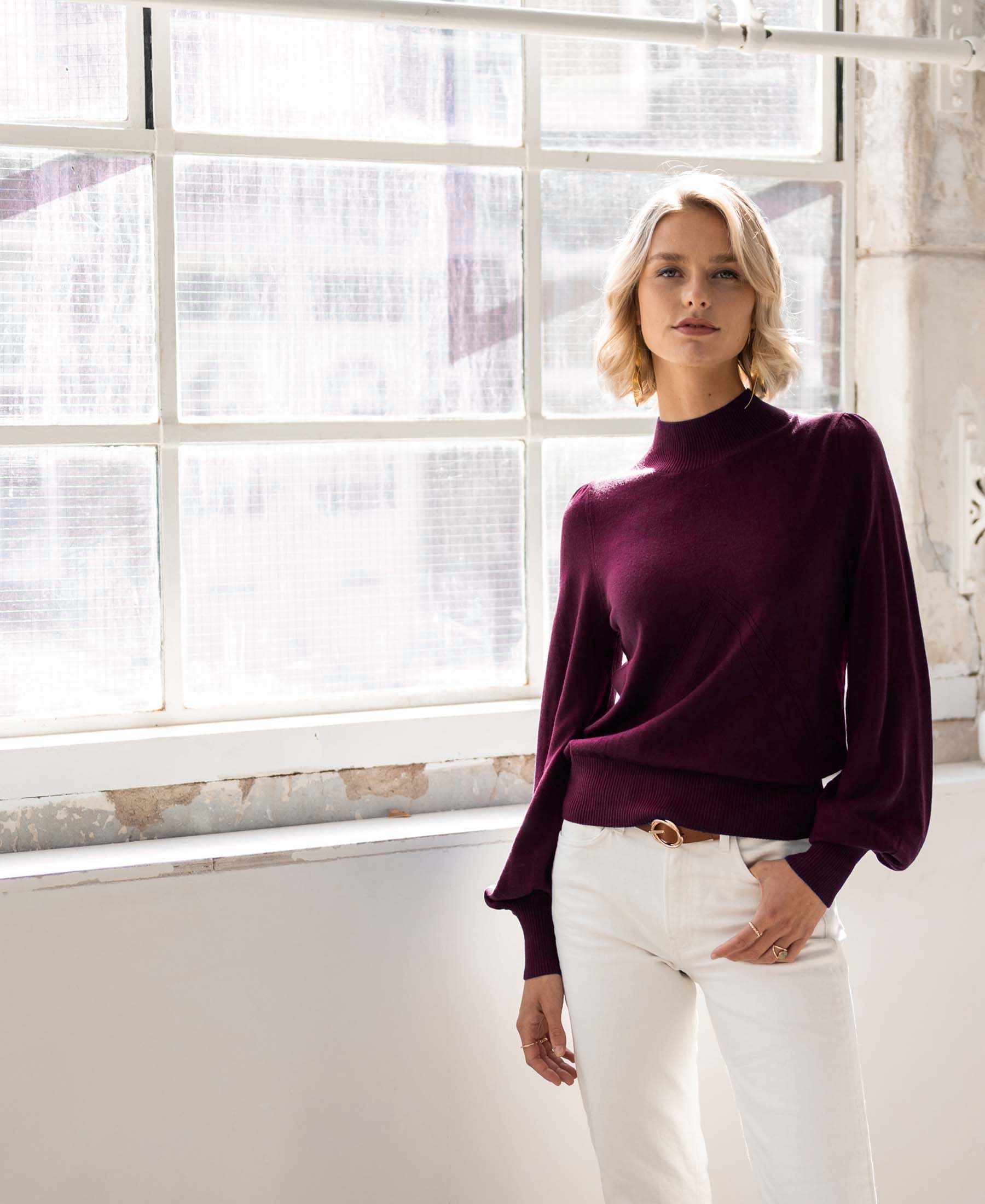 Woman wearing a Bordeaux turtleneck sweater by PLEIN PUBLIQUE, facing the camera.