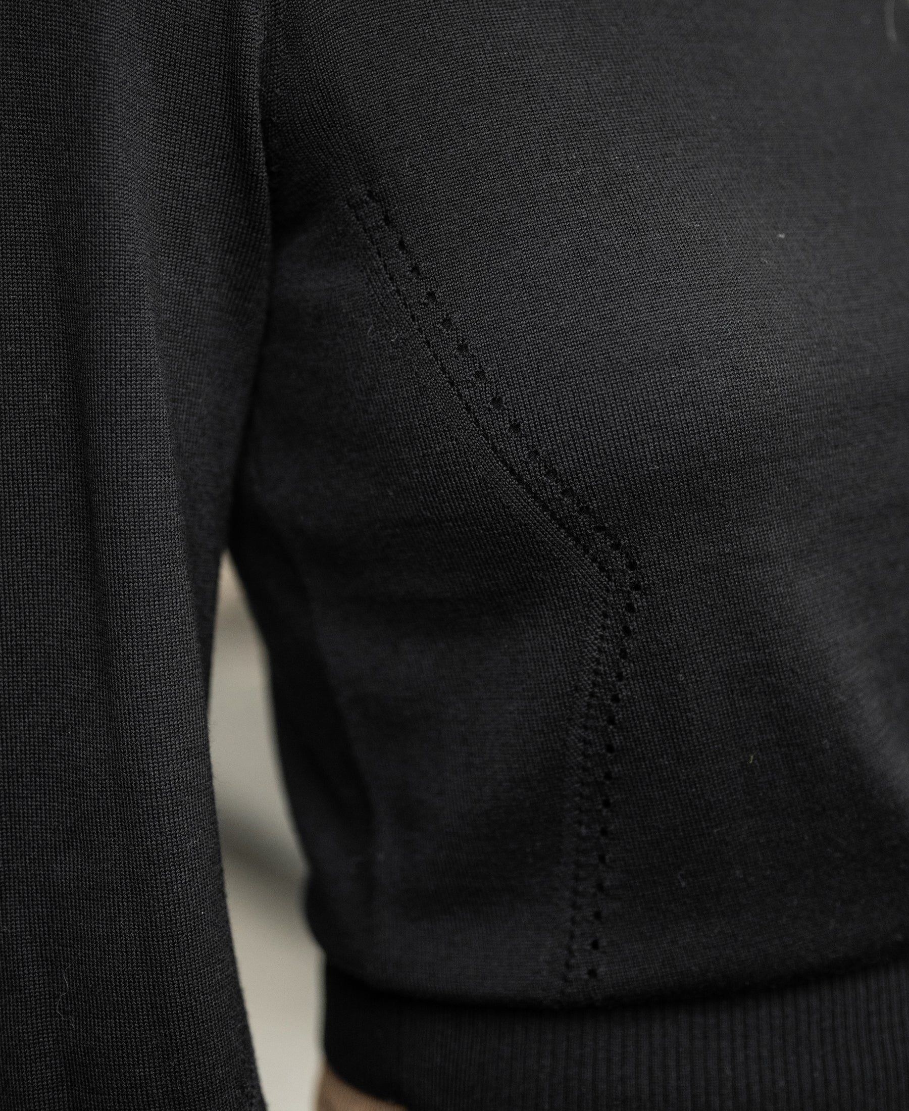 Close-up of the black-gold Merino sweater LA CLIQUE by PLEIN PUBLIQUE with fine stitching and subtle balloon sleeves.