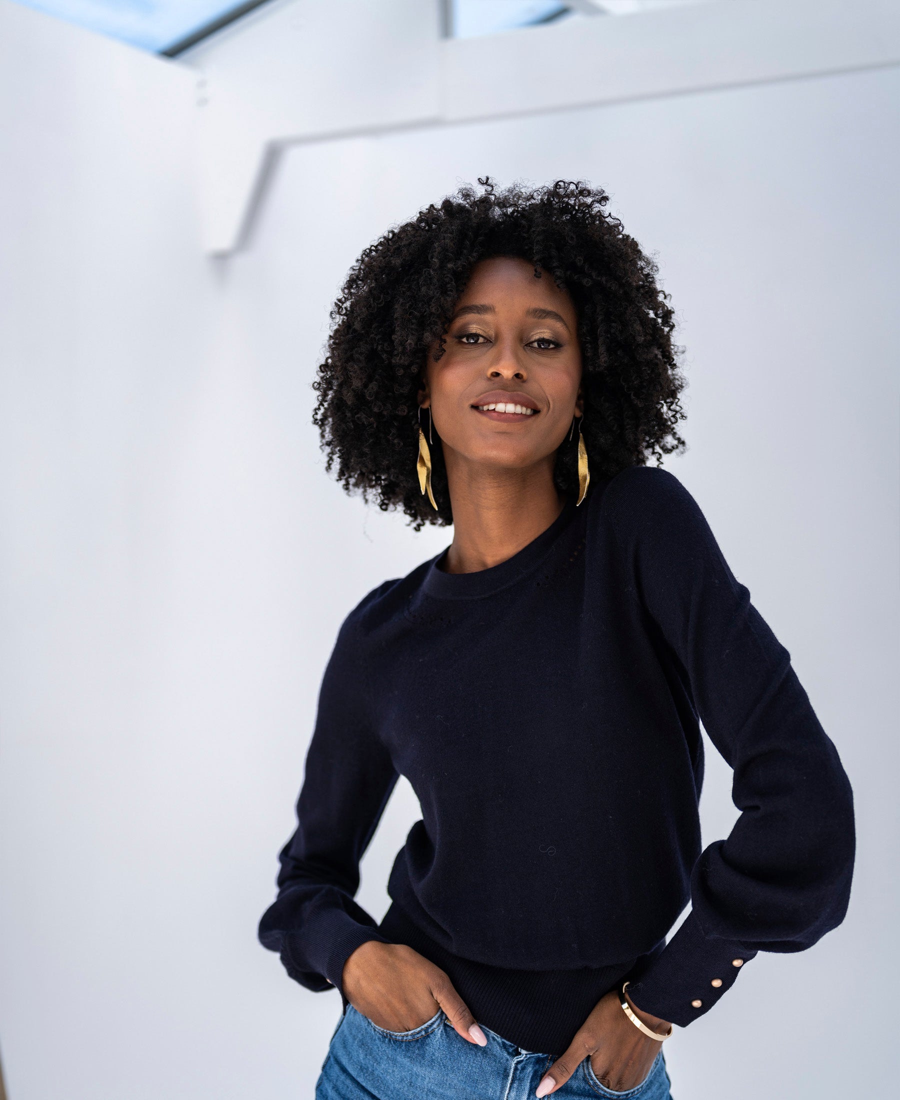 Woman wearing a PLEIN PUBLIQUE LA MARIS merino wool sweater in dark blue and gold.