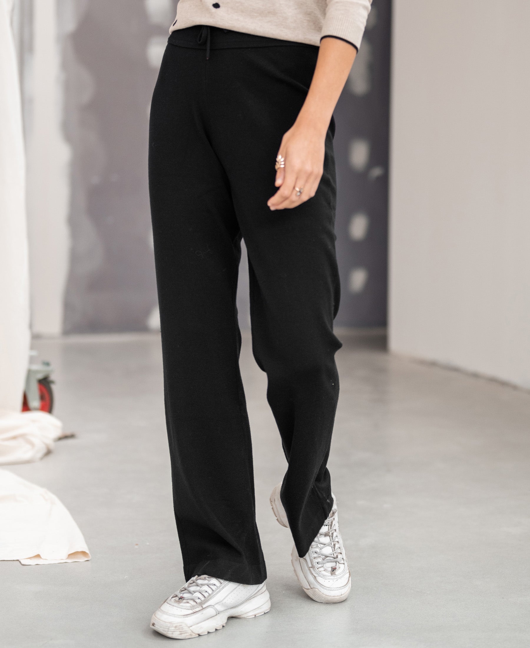 Black knitted pants in the LE LOURDES style by PLEIN PUBLIQUE shown on a gray floor.