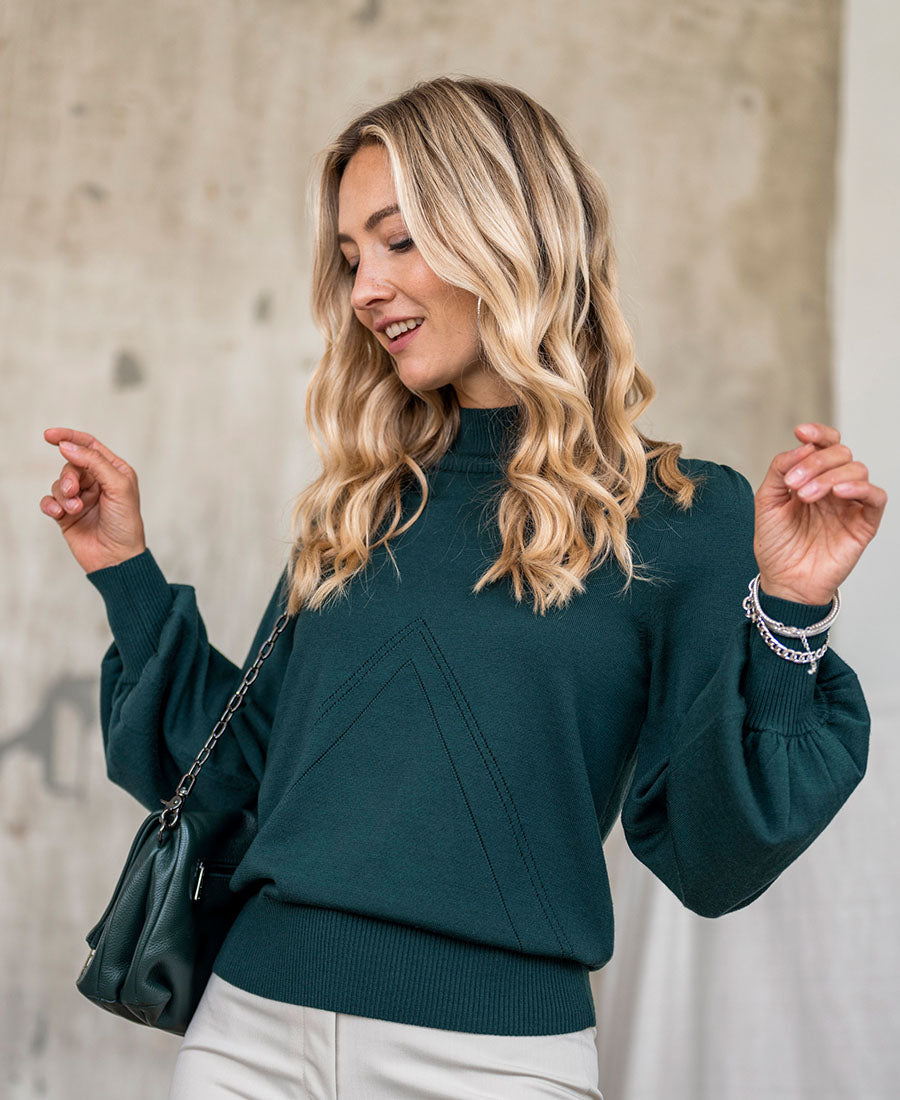 Woman wearing a dark green turtleneck sweater.
