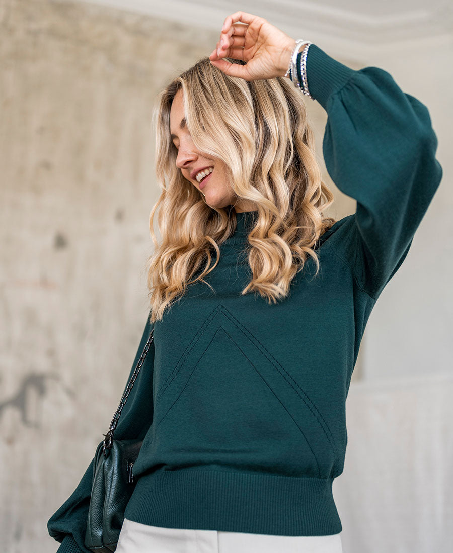 Dark green turtleneck sweater in a relaxed fit shown indoors.