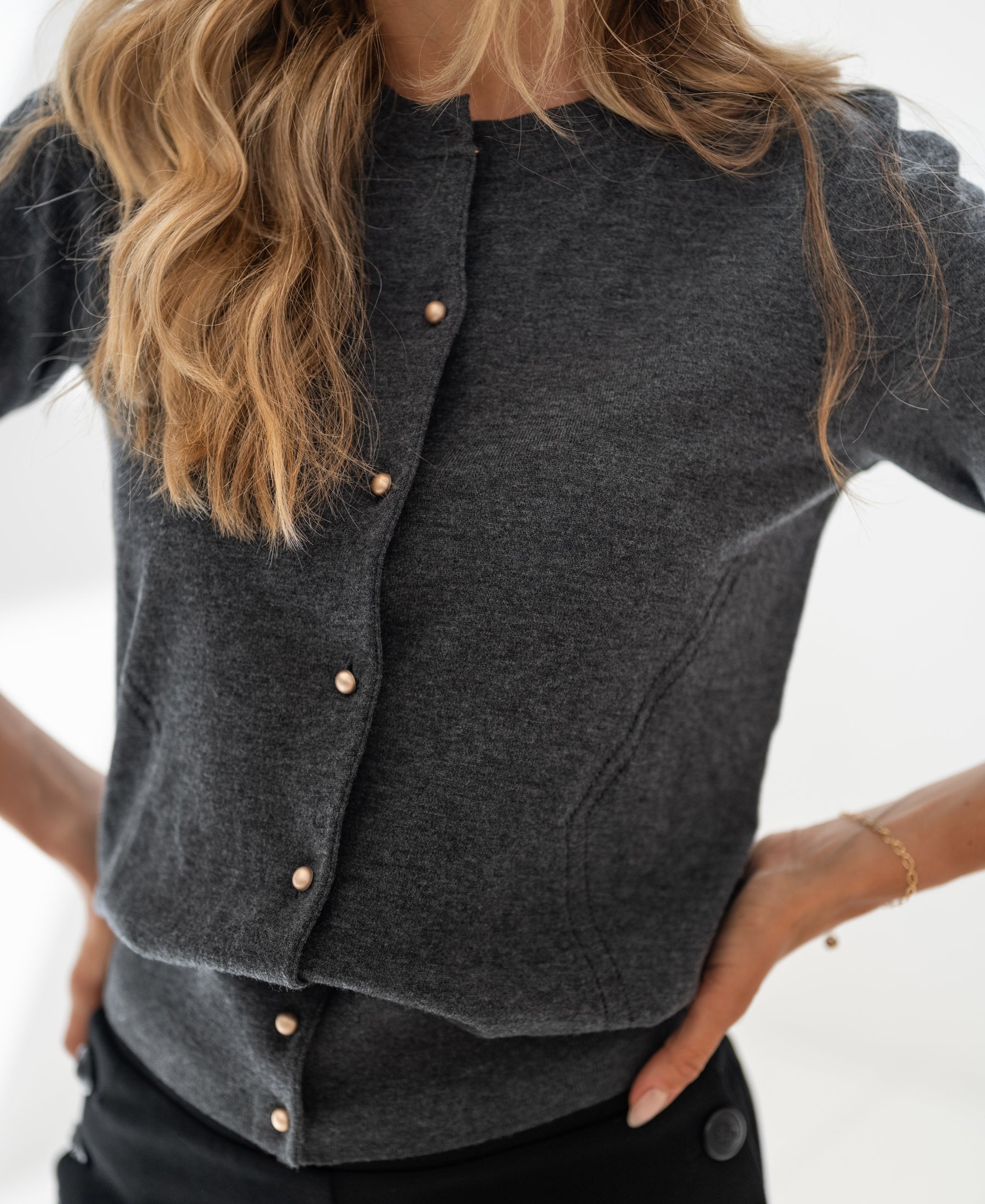 Woman wears PLEIN PUBLIQUE ADELINE cardigan in dark grey with pearl buttons.