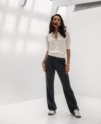 Woman wearing the Adeline vest in ivory white and gunmetal by PLEIN PUBLIQUE in a bright, minimalist room.
