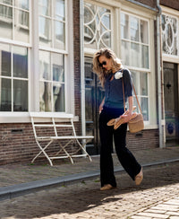 Woman wearing black pull-on trousers walks on a cobblestone street.