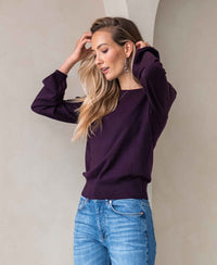 Woman wearing Merino wool LA COEUR Aubergine sweater by PLEIN PUBLIQUE against a neutral background.