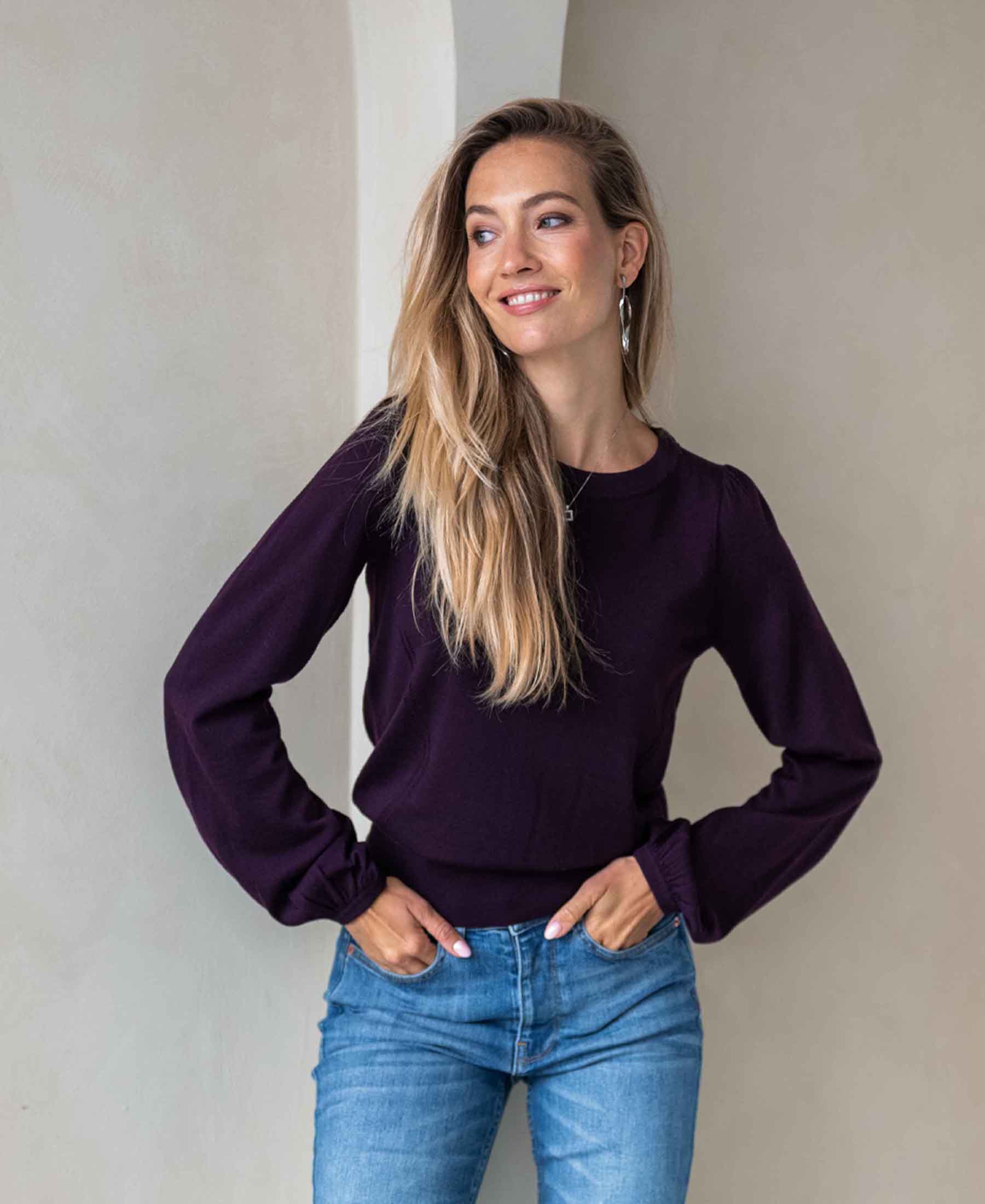 Woman wearing a purple Merino wool sweater against a light background.