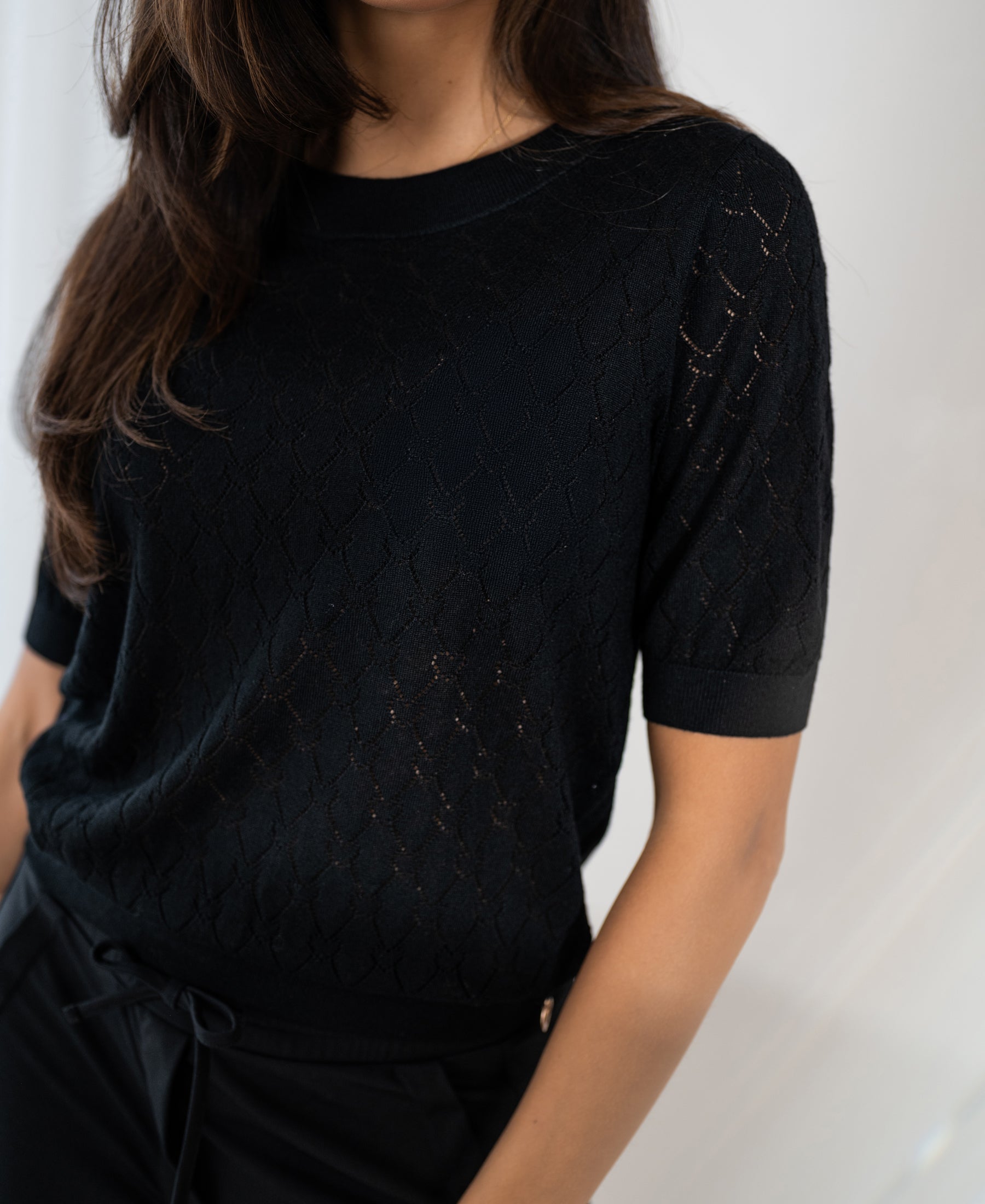Black sweater with heart pattern, shown from shoulders to hips.