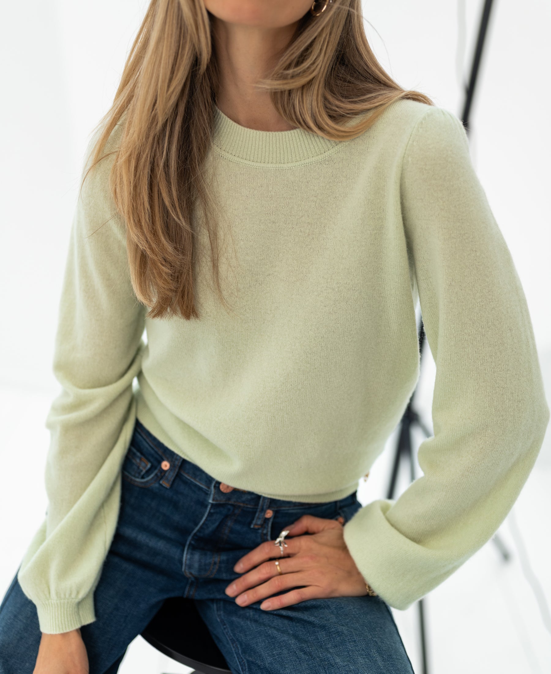 Light green soft merino wool sweater LA BAYONNE by PLEIN PUBLIQUE, shown worn with one hand on hip.