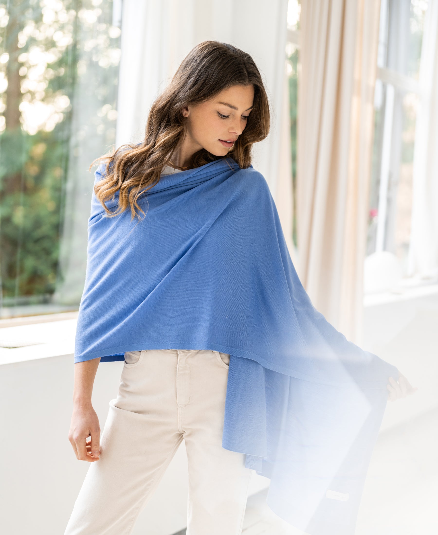 Monaco blue merino wool wrap shawl by PLEIN PUBLIQUE shown indoors in soft light.