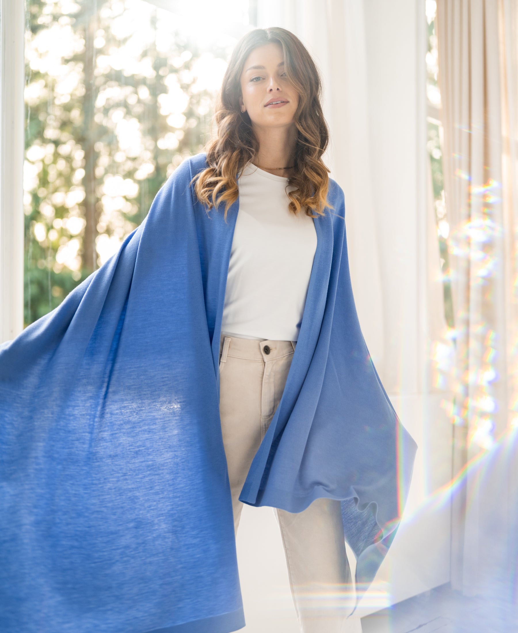 Blue PLEIN PUBLIQUE Merino wool wrap scarf LA BELLA displayed in a sunlit room.